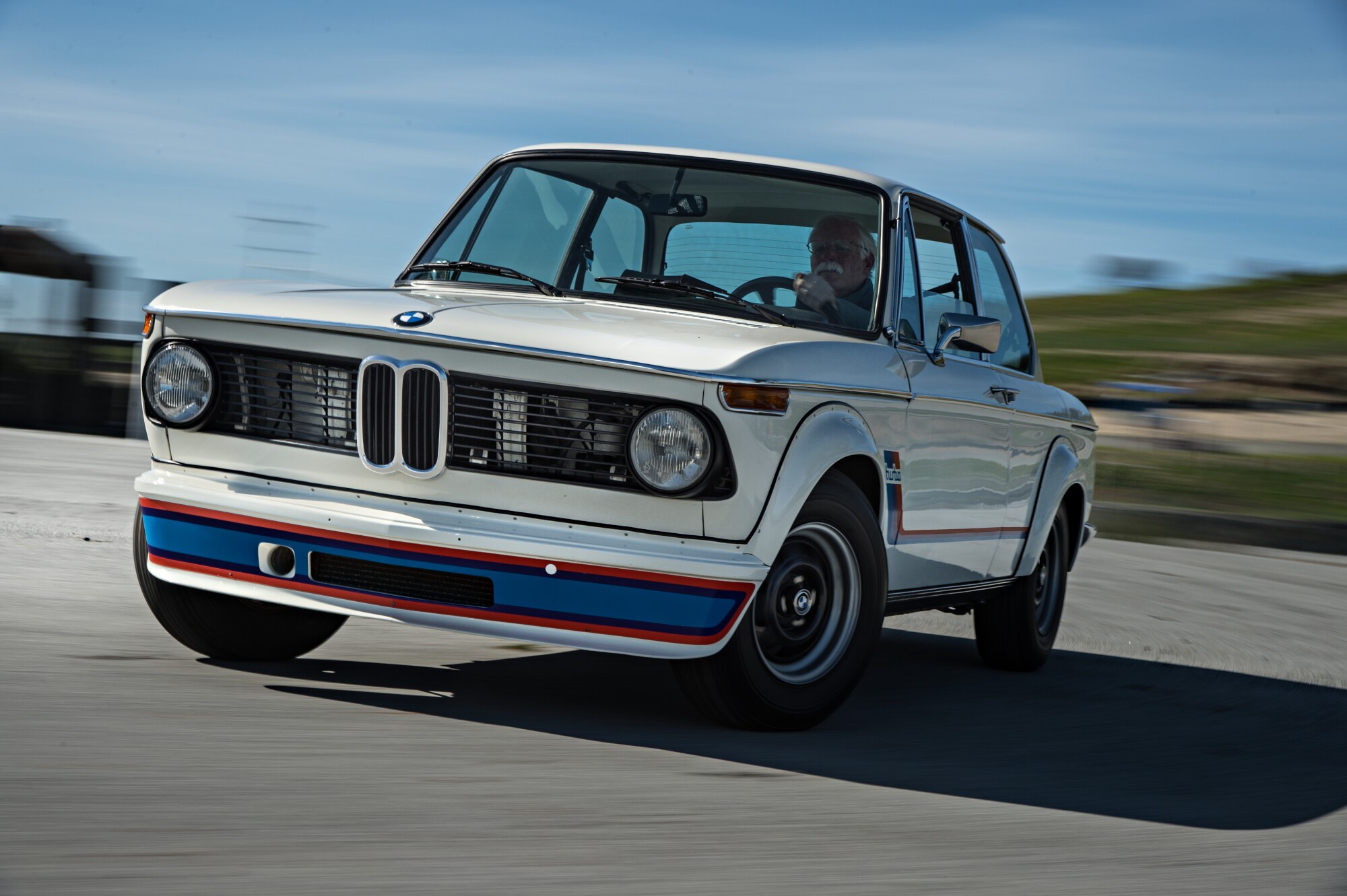 Ein weißer BMW 2002 auf einer Rennstrecke