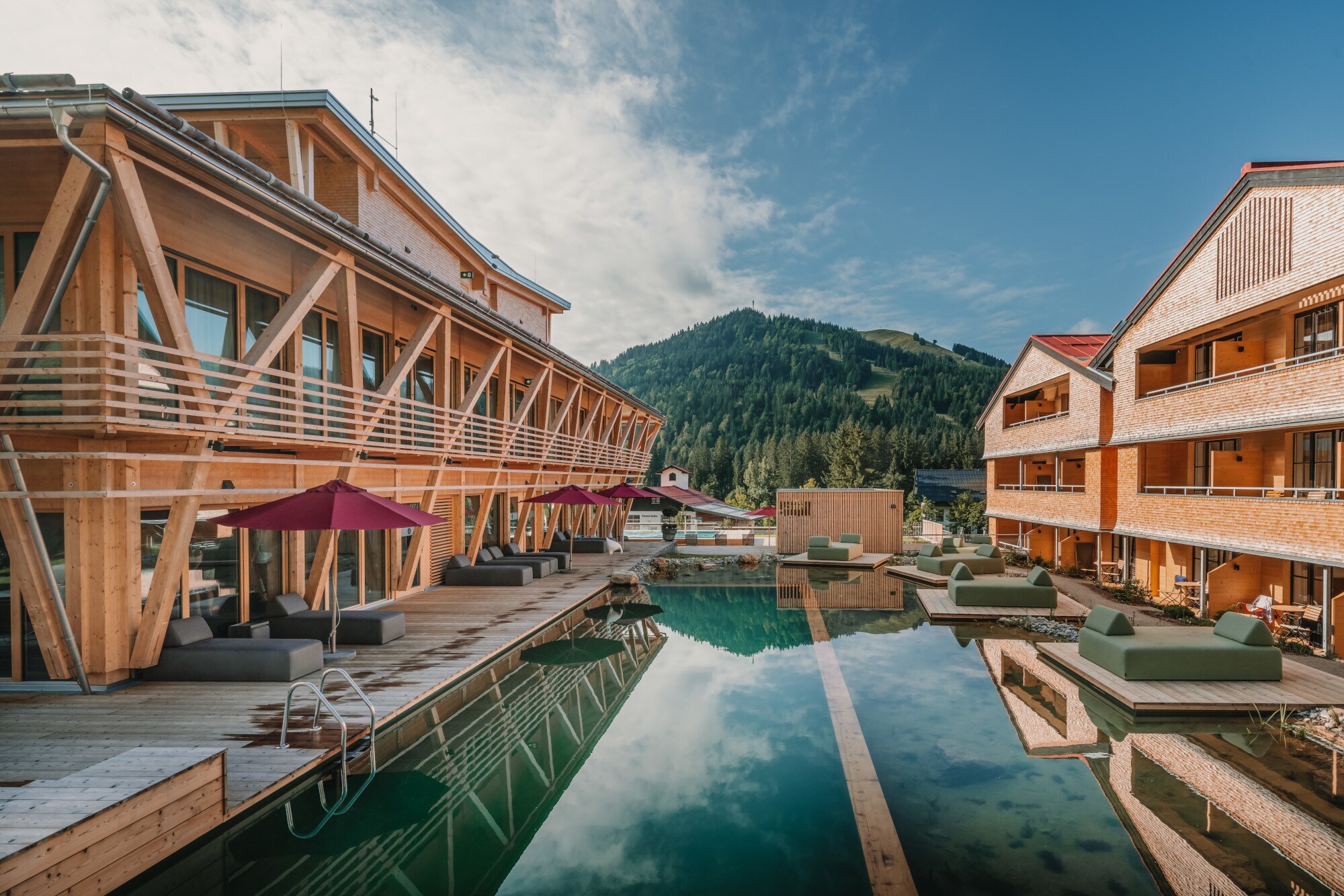 Ein Luxushotelanlage aus Holz mit Außenpool und Blick auf die Berge