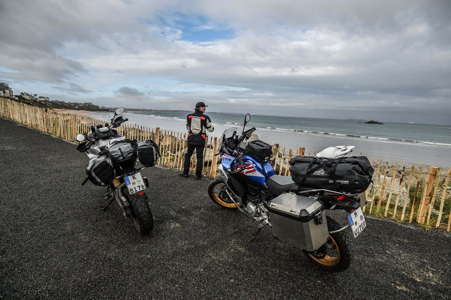 Zwei Motorräder parken vor einem Zaun, im Hintergrund zeichnen sich das Meer und die Umrisse von Saint-Malo ab. Zwei Motorräder parken vor einem Zaun, im Hintergrund zeichnen sich das Meer und die Umrisse von Saint-Malo ab.
