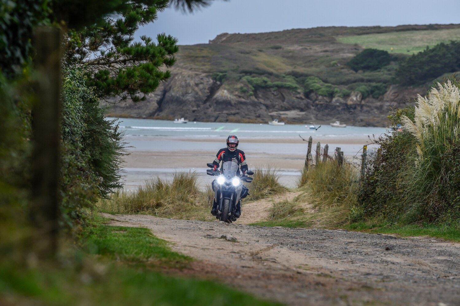 Ein Motorradfahrer auf einem Schotterweg an einer rauen Küste