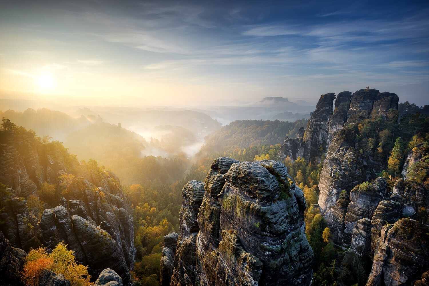 Blick auf das Elbsandsteingebirge mit Nebelschwaden bei Sonnenuntergang.