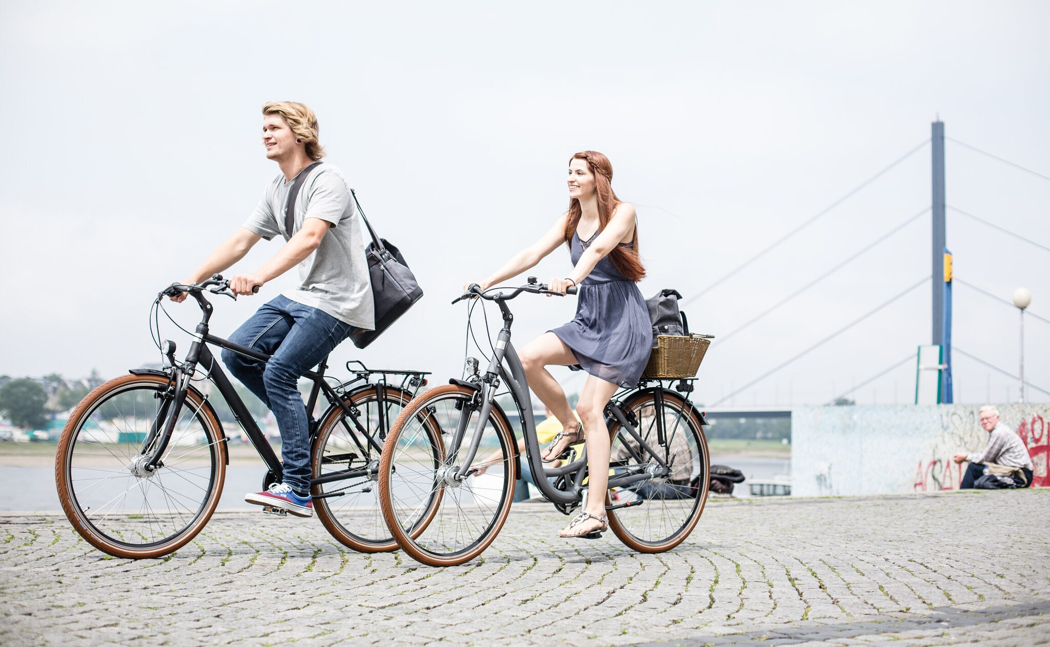 Ein junges Paar fährt an einem Fluß mit dem Rad. Ein junges Paar fährt an einem Fluß mit dem Rad.