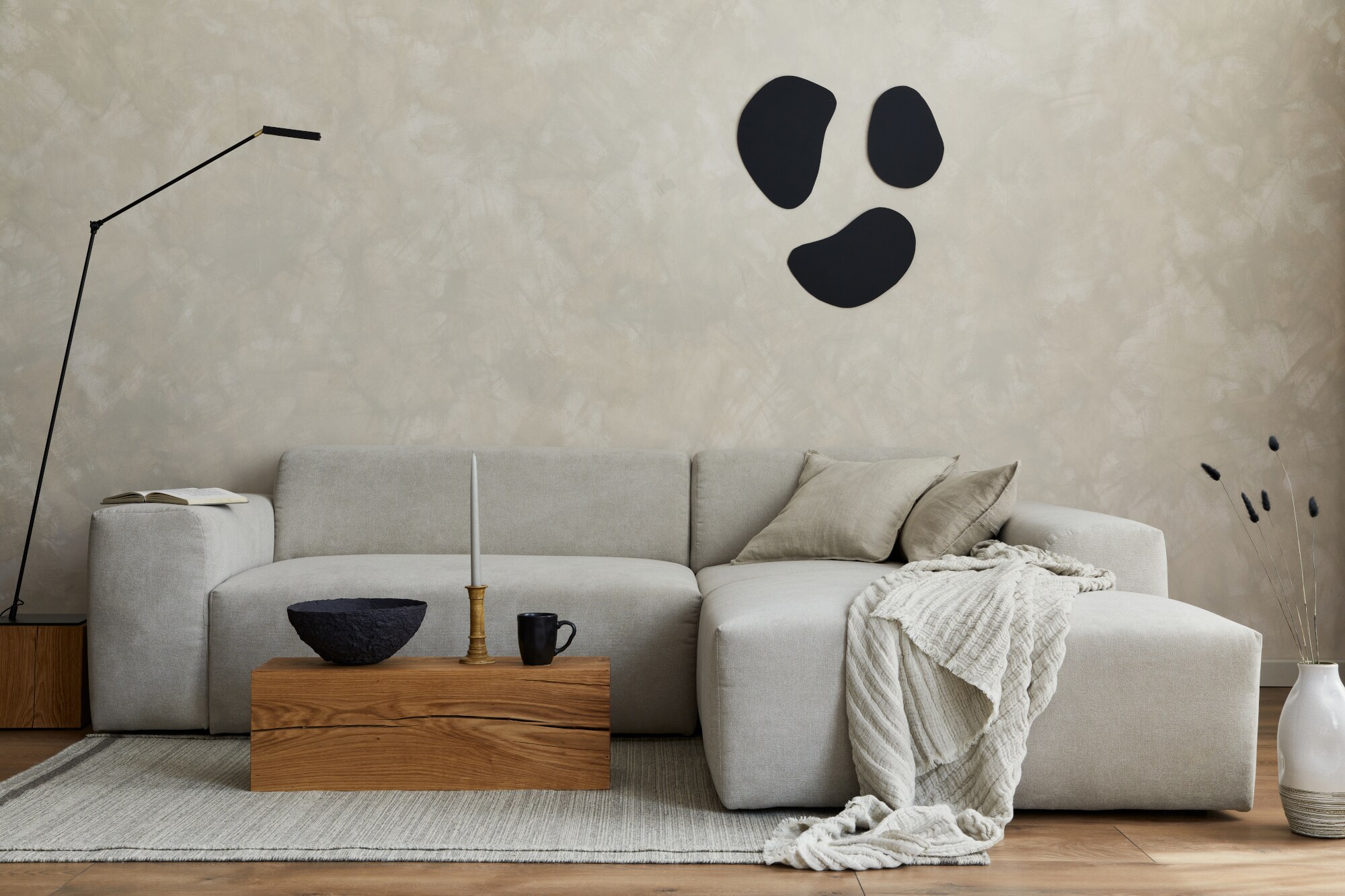 Stilvolle Wohnzimmer-Inszenierung im Japandi-Stil mit einem grauen Stoffsofa, Holzwürfel und eleganten Accessoires Stilvolle Wohnzimmer-Inszenierung im Japandi-Stil mit einem grauen Stoffsofa, Holzwürfel und eleganten Accessoires
