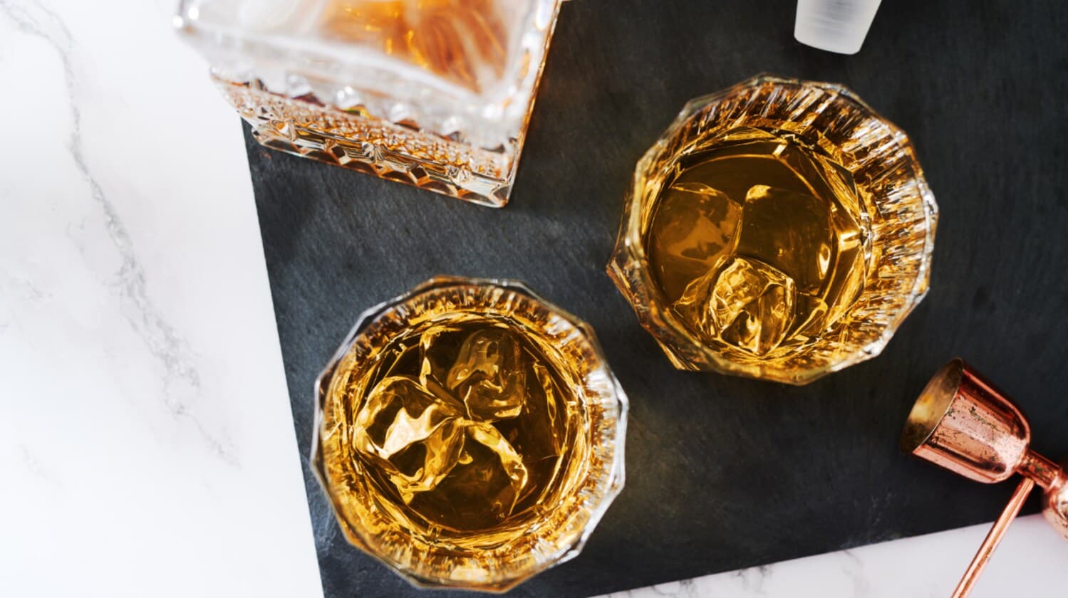 Aufsicht von zwei gefüllten Whiskygläsern mit Eis auf einer Schieferplatte Aufsicht von zwei gefüllten Whiskygläsern mit Eis auf einer Schieferplatte