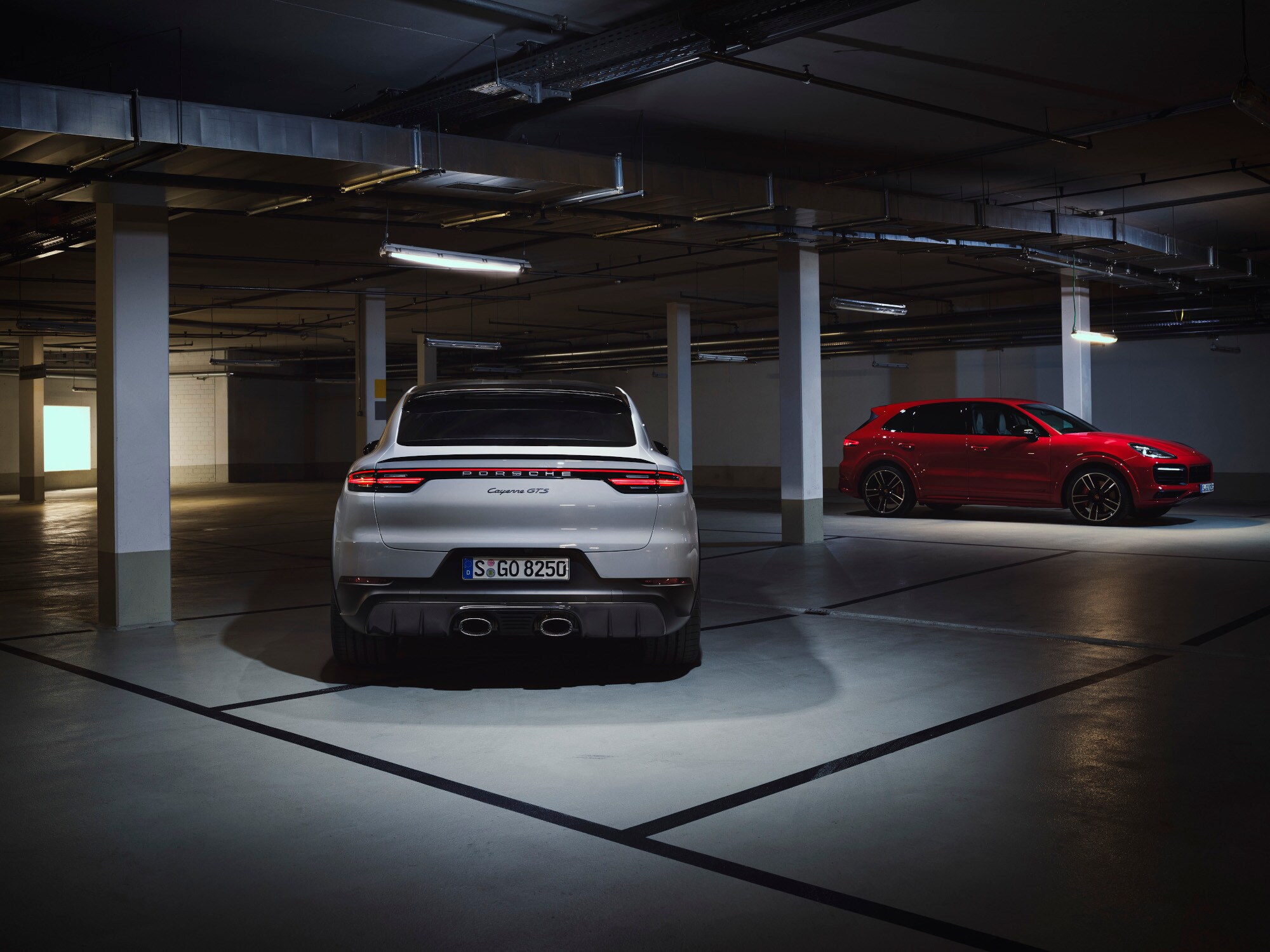 Ein weißer und ein roter Porsche in einer Tiefgarage