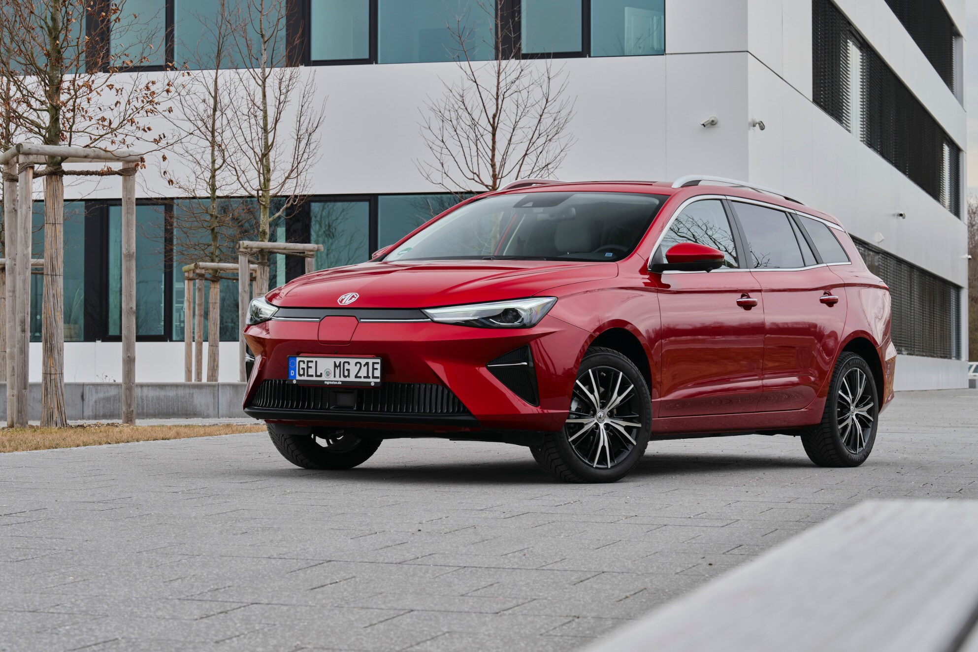 Roter Kombi vor einem großen grauen Haus