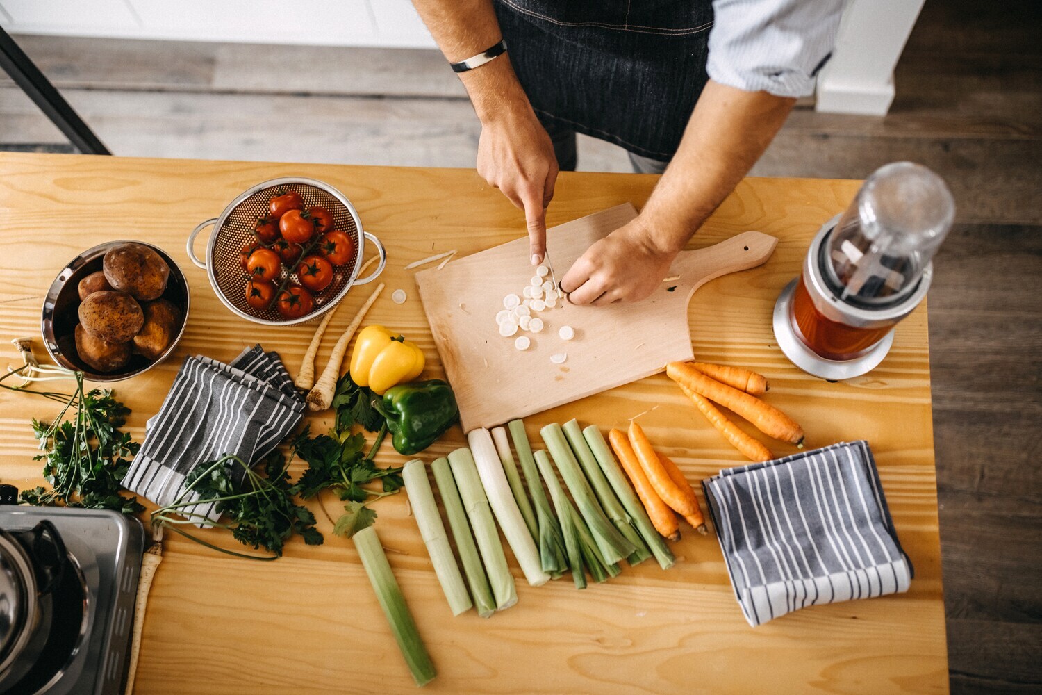 Eine Person aus der Aufsicht fotografiert, die eine Mahlzeit aus Gemüse zubereitet.