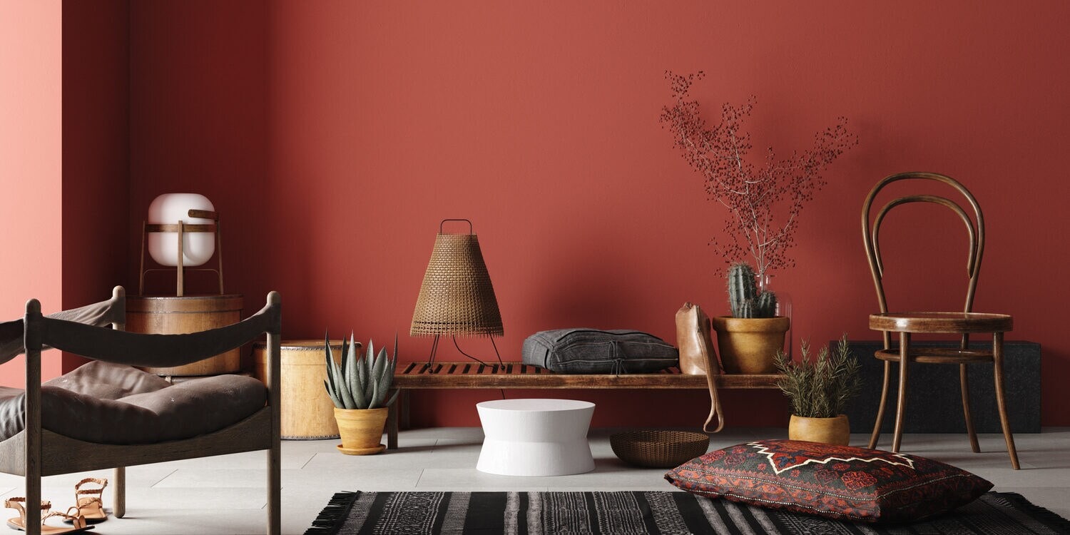 Interieur mit Möbeln und Objekten in Erdtönen vor einer terrakottafarben Wand Interieur mit Möbeln und Objekten in Erdtönen vor einer terrakottafarben Wand