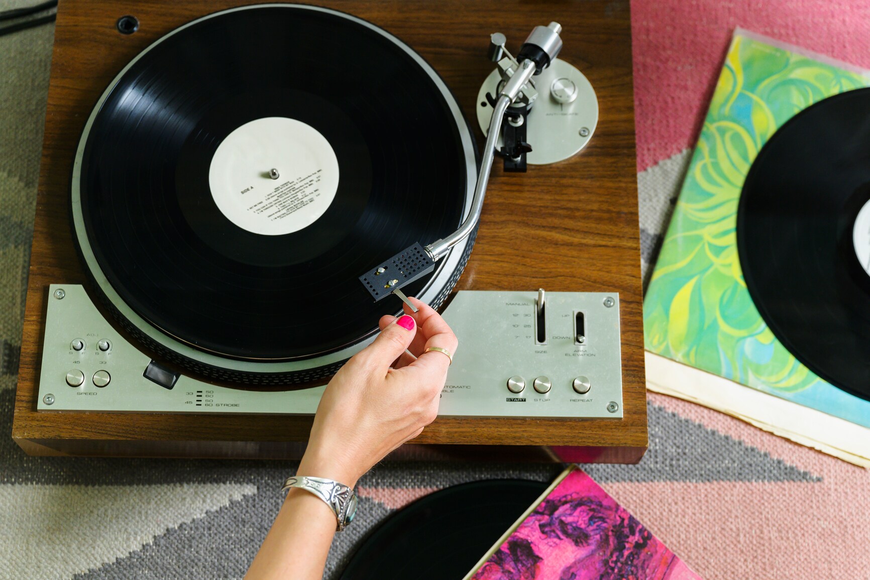 Eine Hand bewegt den Tonarm eines Plattenspielers aus Holz Eine Hand bewegt den Tonarm eines Plattenspielers aus Holz