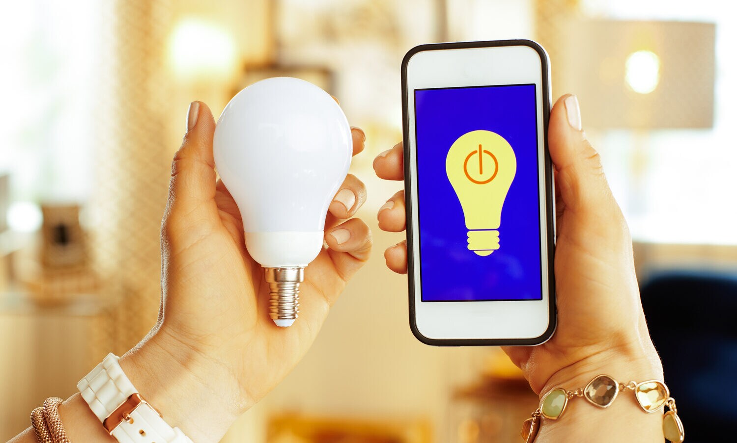Smartphone mit Smarthome-App und smarter Glühbirne in Händen Smartphone mit Smarthome-App und smarter Glühbirne in Händen