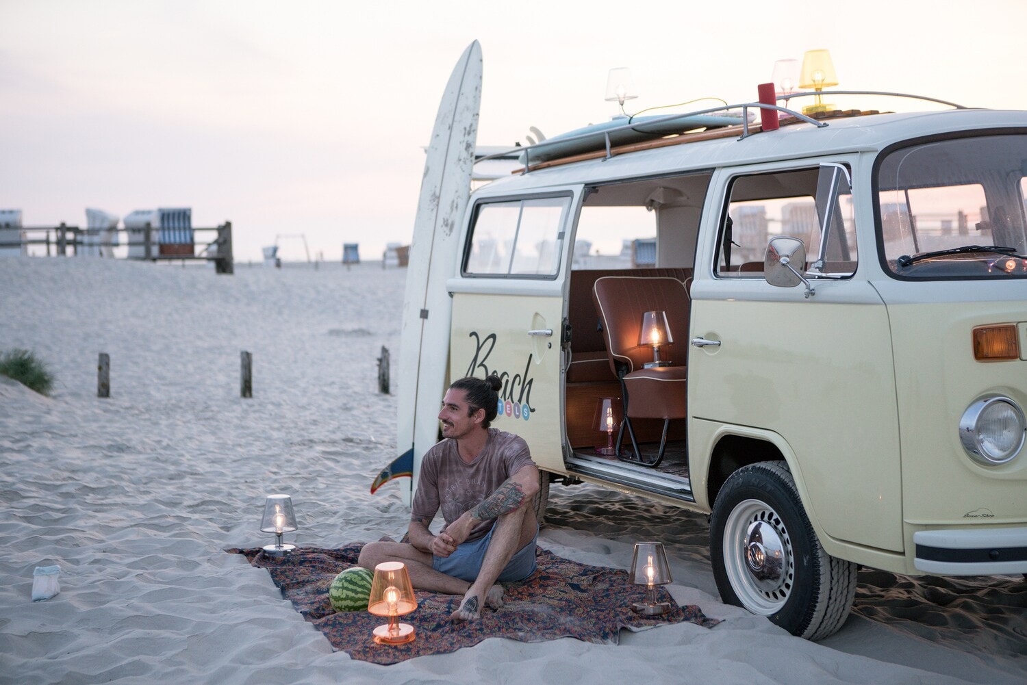 Ein Mann sitzt vor seinem Bulli im Sand am Strand. Ein Mann sitzt vor seinem Bulli im Sand am Strand.