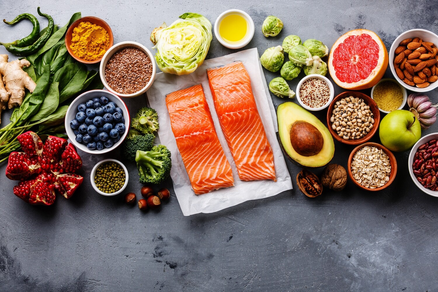 Gesunde Lebensmittel wie Lachs, Avocado, Granatapfel und mehr nebeneinander. Gesunde Lebensmittel wie Lachs, Avocado, Granatapfel und mehr nebeneinander.