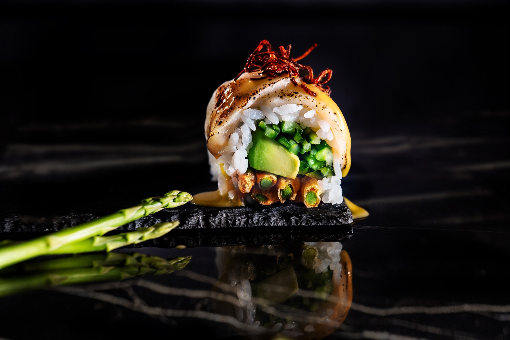 Kunstvoll angerichtetes Sushi mit grünem Spargel als Deko Kunstvoll angerichtetes Sushi mit grünem Spargel als Deko