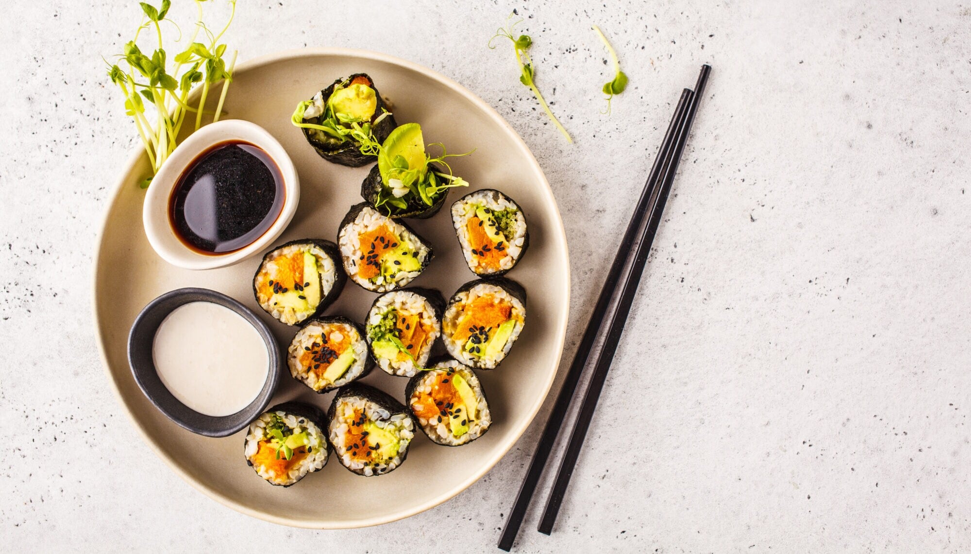 Vegane Sushi-Rollen auf einem Teller mit Sojasauce, Dip und Stäbchen Vegane Sushi-Rollen auf einem Teller mit Sojasauce, Dip und Stäbchen