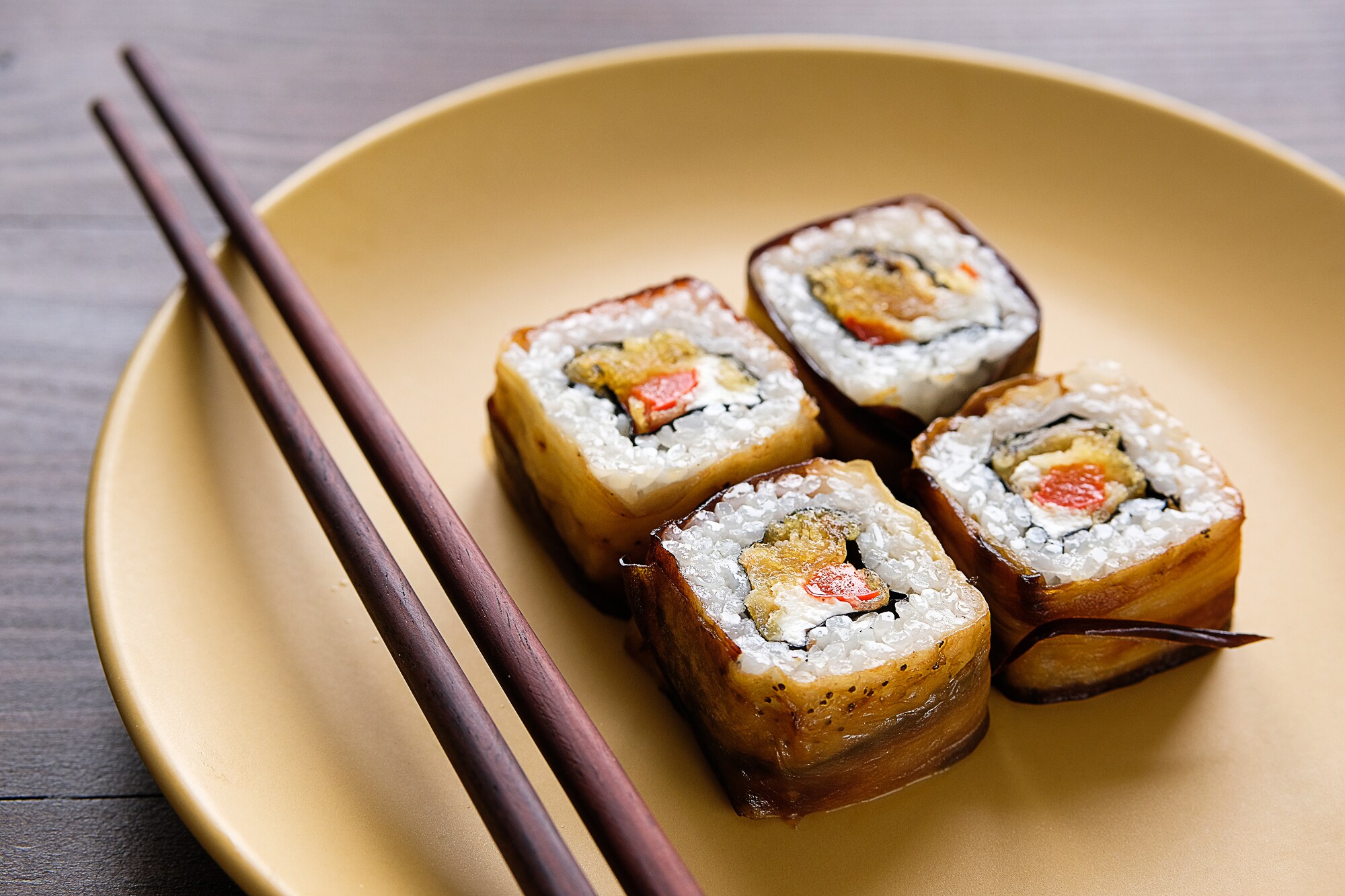 Veganes Sushi auf einem runden Teller mit Stäbchen