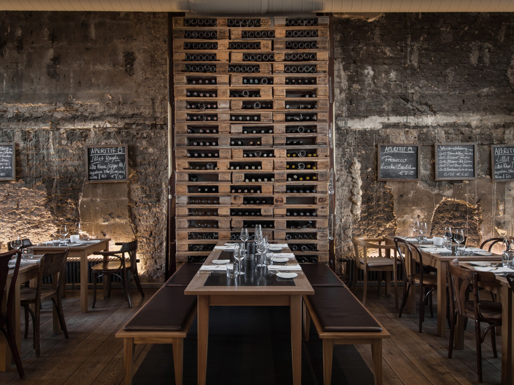 Hohes Weinregal neben rustikaler Steinmauer im Restaurant das ACHT