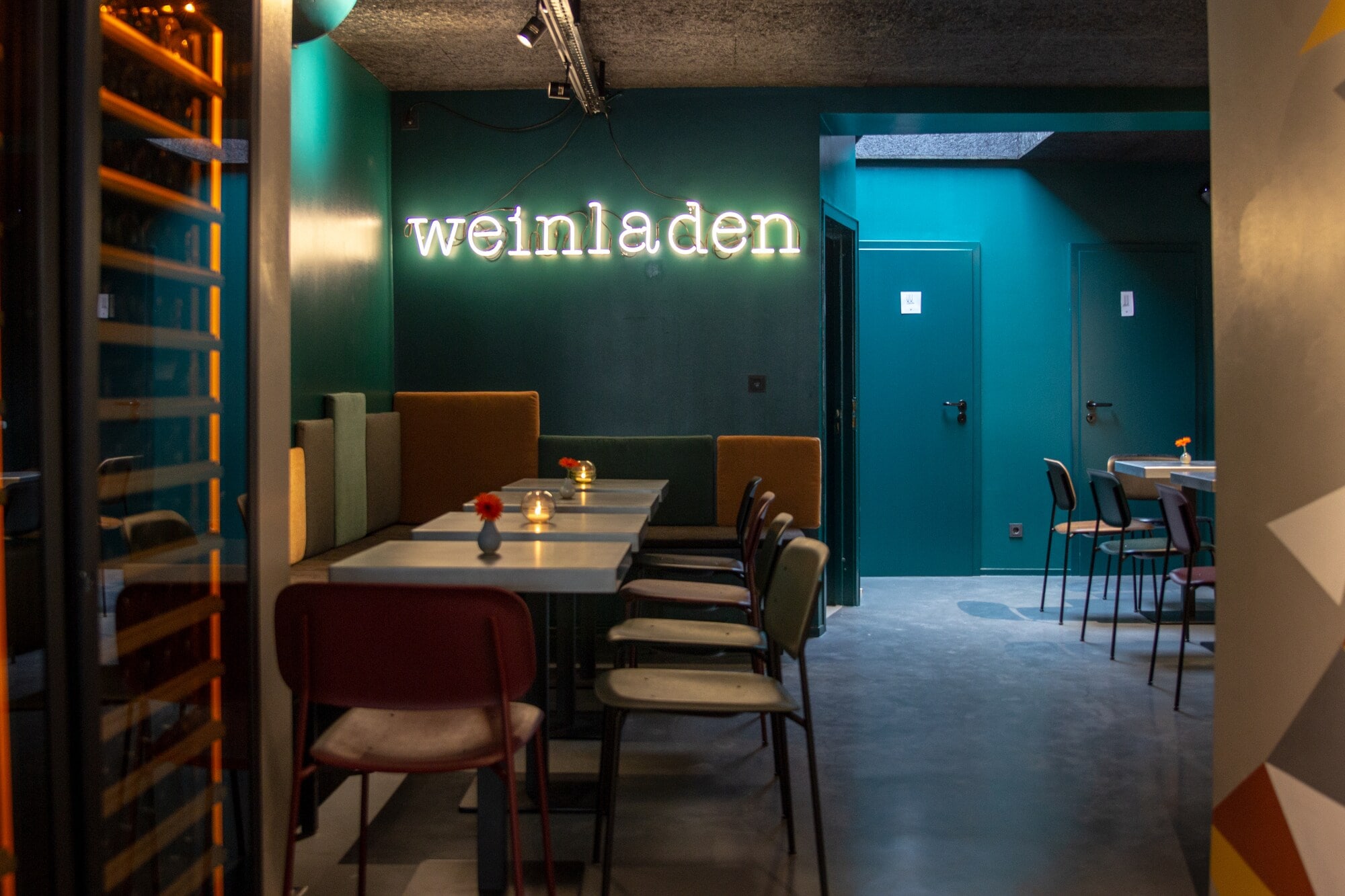 Restauranttische unter dem beleuchteten Schriftzug weinladen in Köln Restauranttische unter dem beleuchteten Schriftzug weinladen in Köln