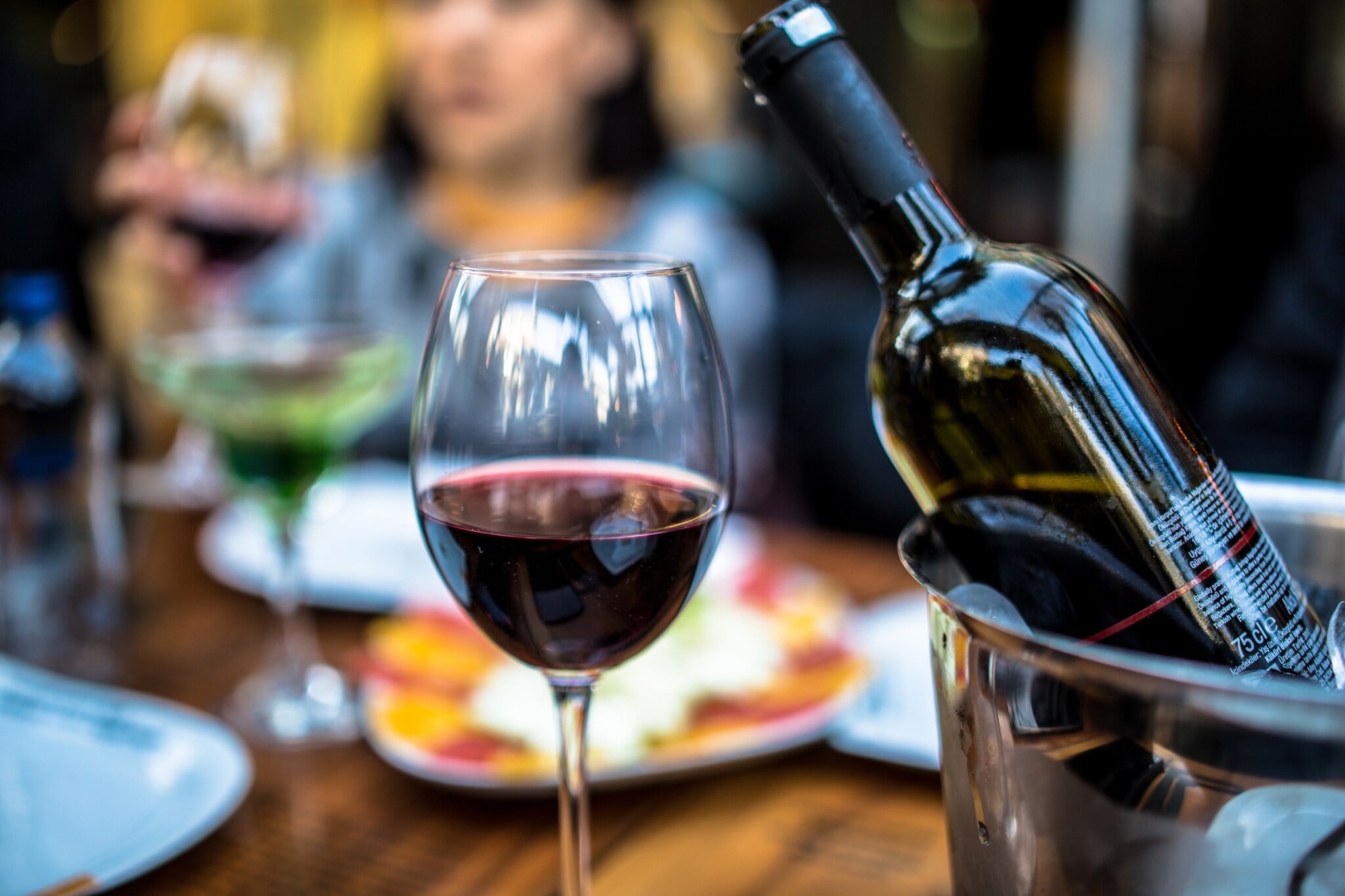 Ein gefülltes Glas Rotwein neben einem Weinkühler. Ein gefülltes Glas Rotwein neben einem Weinkühler.