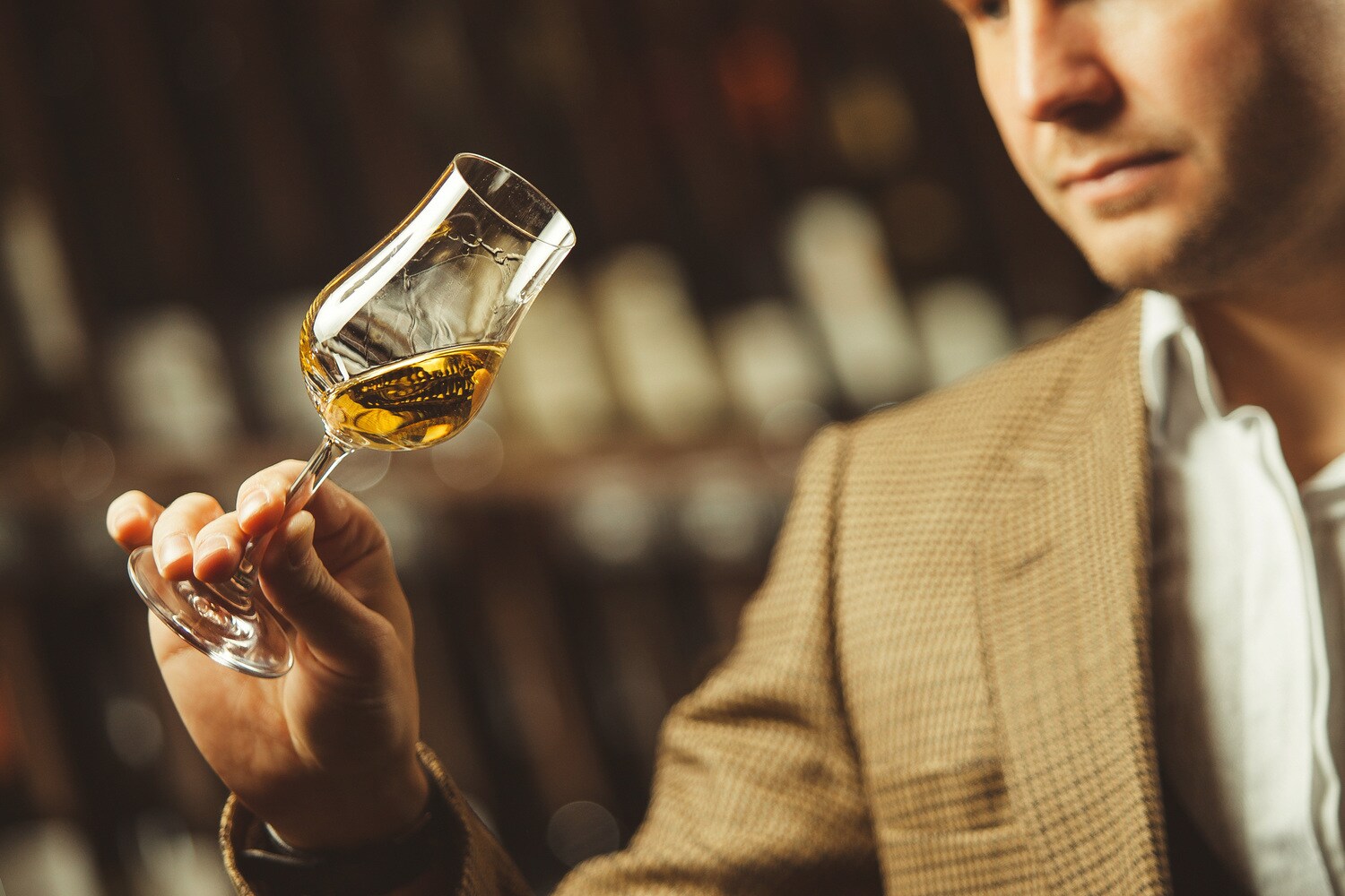 Ein Mann schwenkt ein Whisky Nosing Glas in seiner Hand