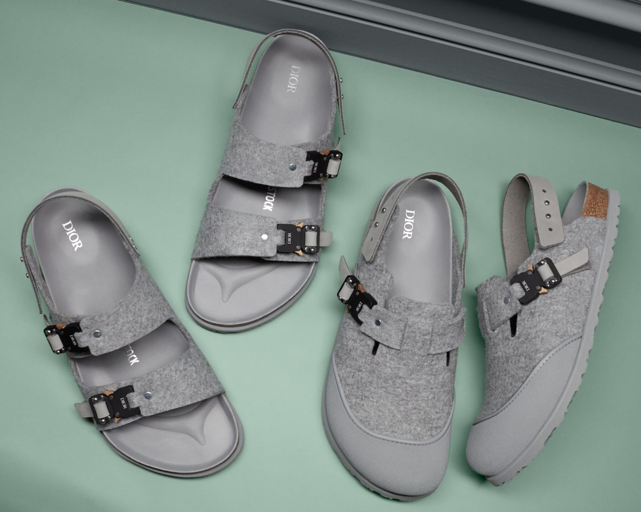 Detailaufnahme von zwei Paar grauer Sandalen mit Dior- und Birkenstock-Logo Detailaufnahme von zwei Paar grauer Sandalen mit Dior- und Birkenstock-Logo