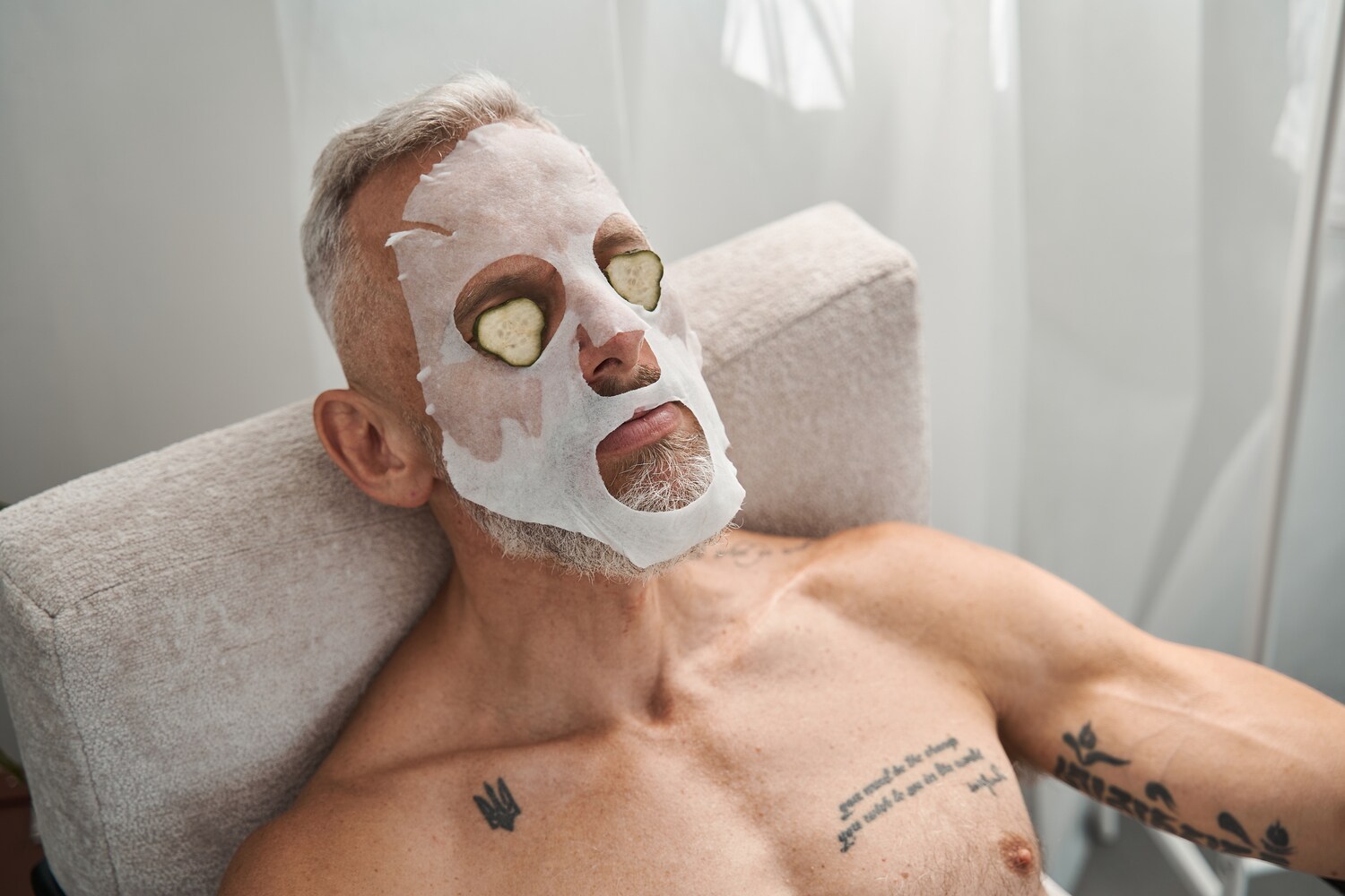 Ein Mann mit Schönheitsmaske und Gurke im Gesicht. Ein Mann mit Schönheitsmaske und Gurke im Gesicht.