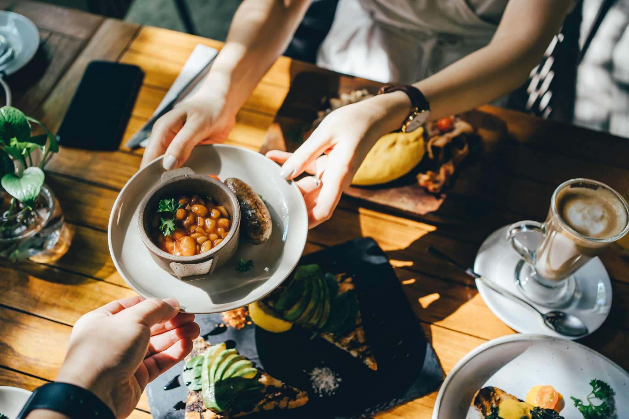 Hände reichen bei einem Brunch in Berlin eine Schale mit Essen Hände reichen bei einem Brunch in Berlin eine Schale mit Essen