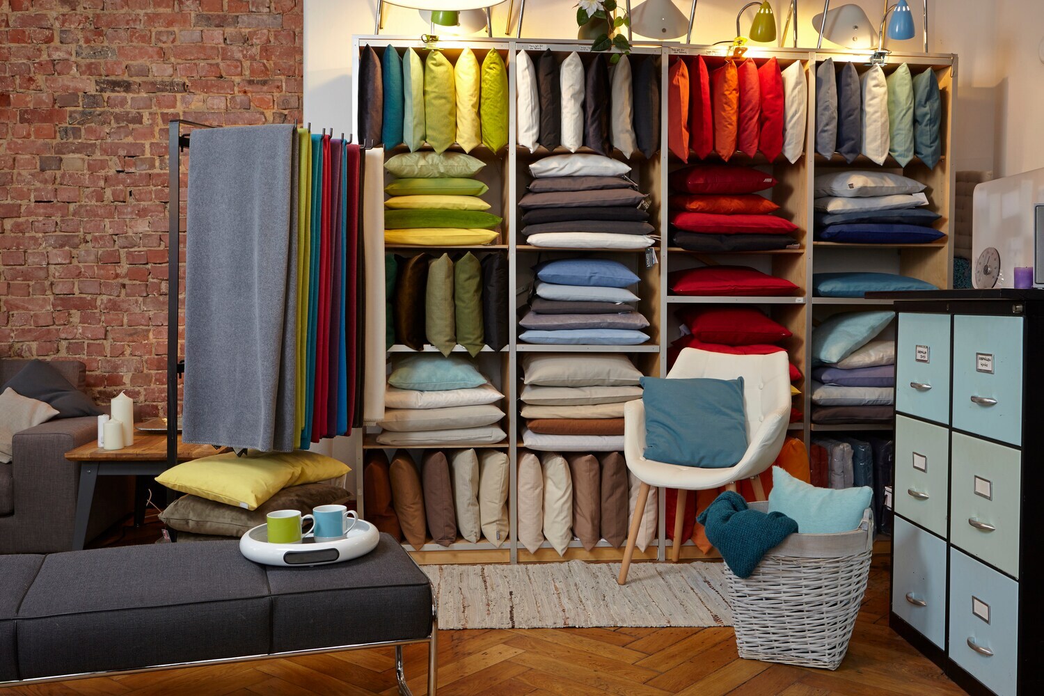 Ein Regal gefüllt mit vielen bunten Kissen, dazu weitere Einrichtungsgegenstände.