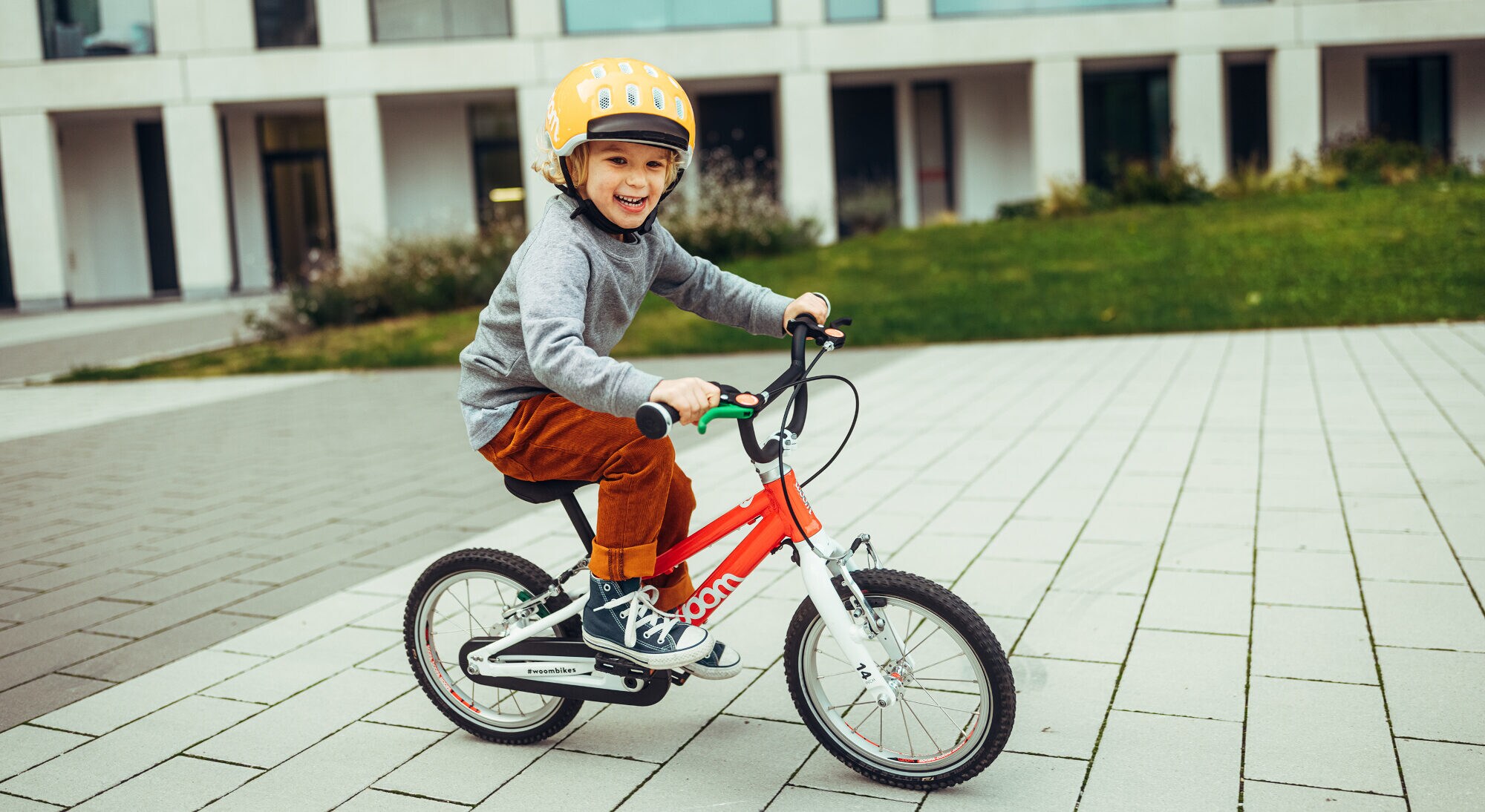 Ein kleiner Junge fährt auf seinem Fahrrad vor einem Wohnhaus