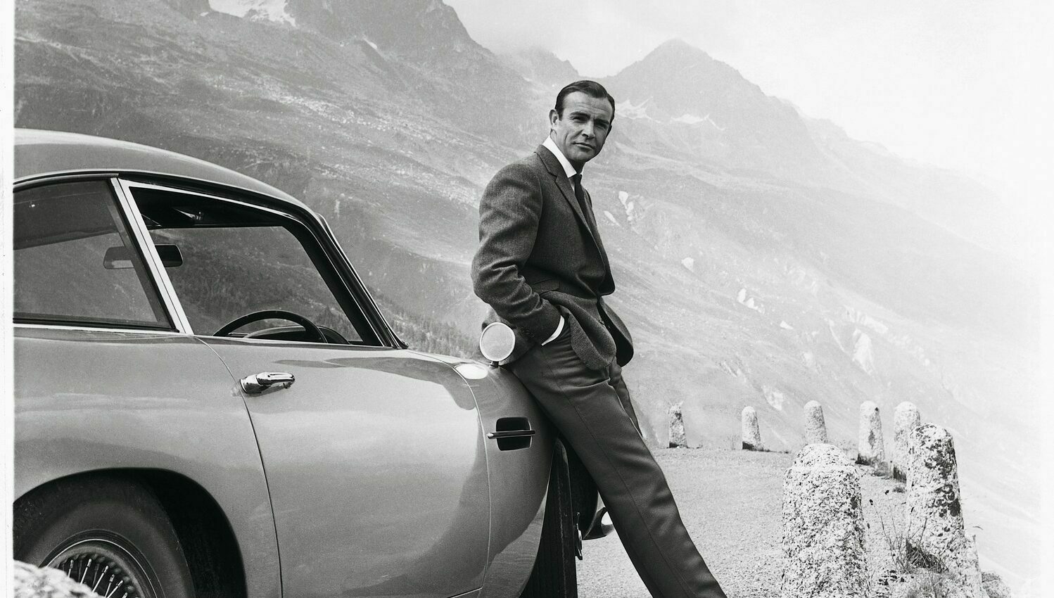 Sean Connery lehnt in der Rolle des James Bond an einem Aston Martin