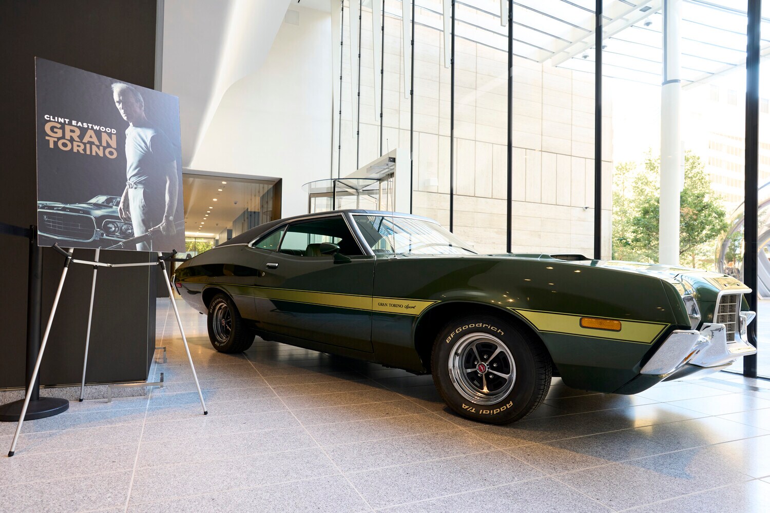 Das Filmauto aus Gran Torino und ein Filmplakat auf einer Ausstellungsfläche Das Filmauto aus Gran Torino und ein Filmplakat auf einer Ausstellungsfläche