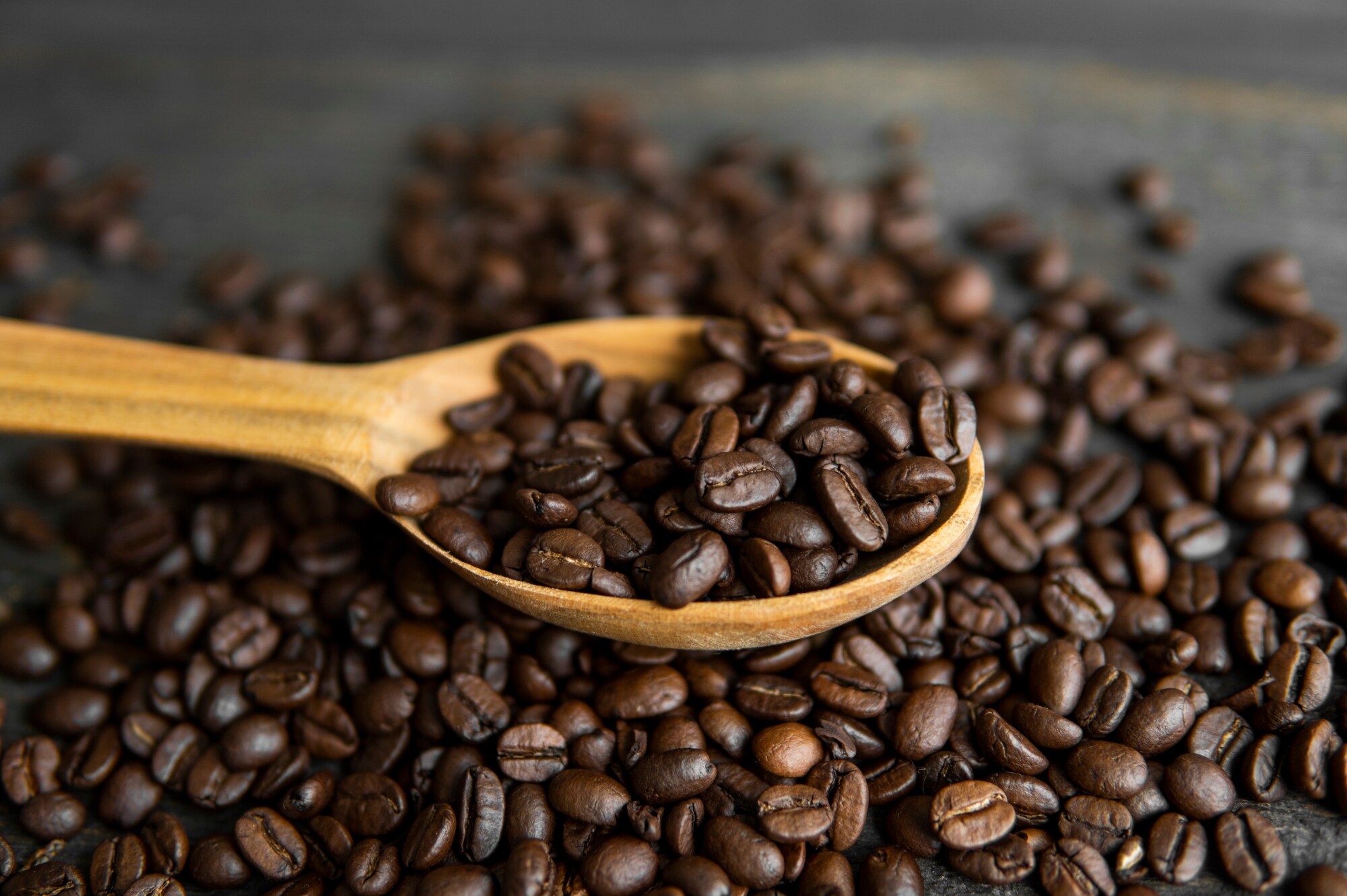 Kaffeebohnen und ein Holzlöffel, der mit Bohnen gefüllt ist