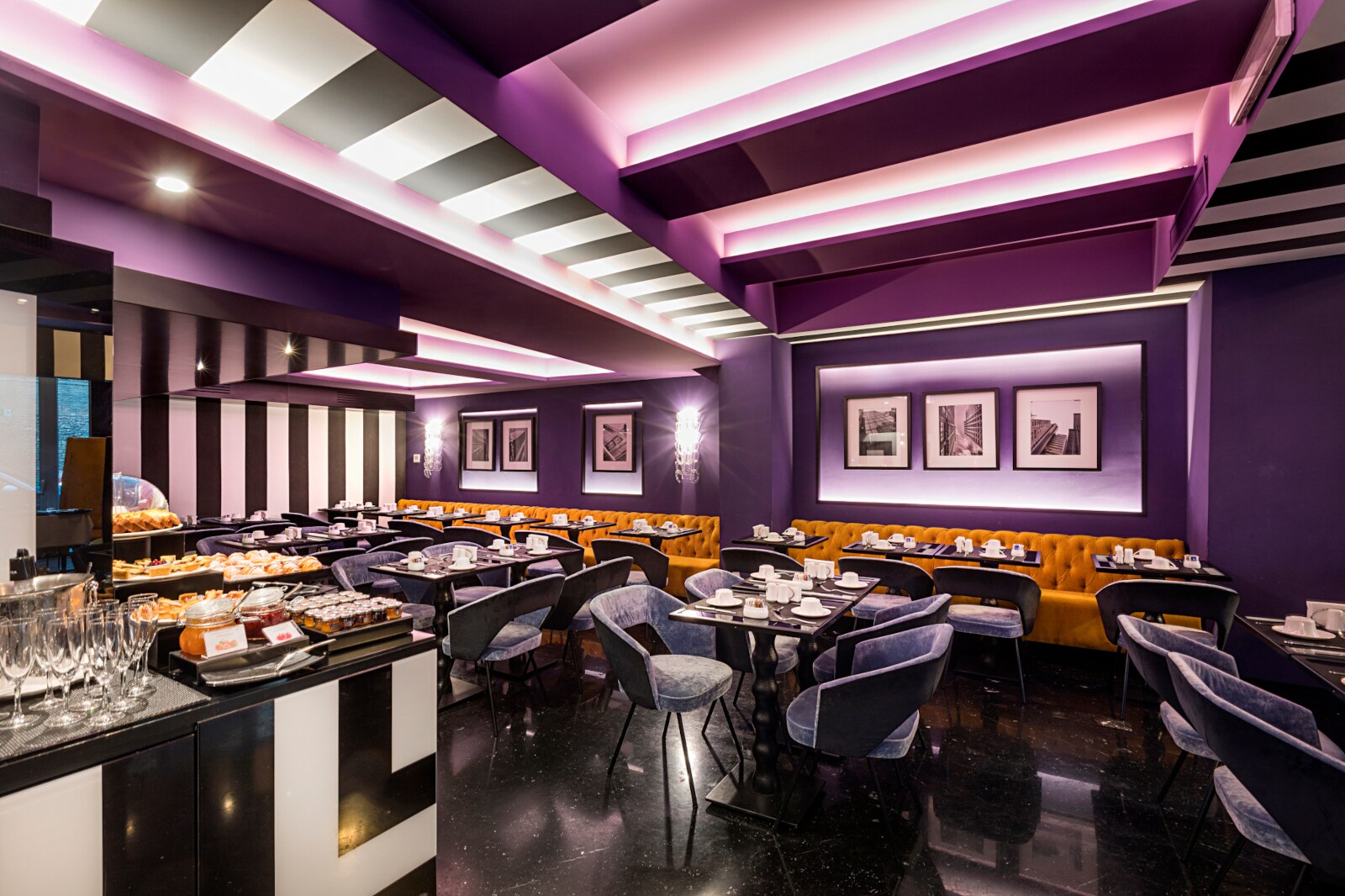 Innenraum des Restaurants The Tribune mit lila Wänden und Polsterstühlen aus Samt