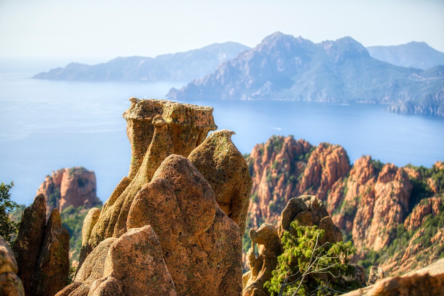 Interessante Felsformationen vor traumhafter Kulisse mit Meer und Bergen am Horizont.