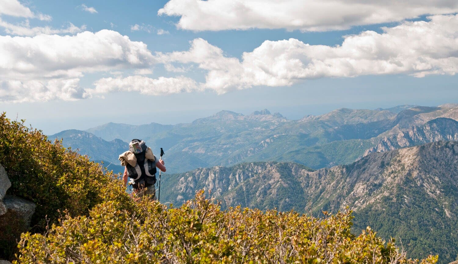 Ein Mann wandert in großer Höhe über einen Berg, dazu Panoramablick über das Gebirge. Ein Mann wandert in großer Höhe über einen Berg, dazu Panoramablick über das Gebirge.
