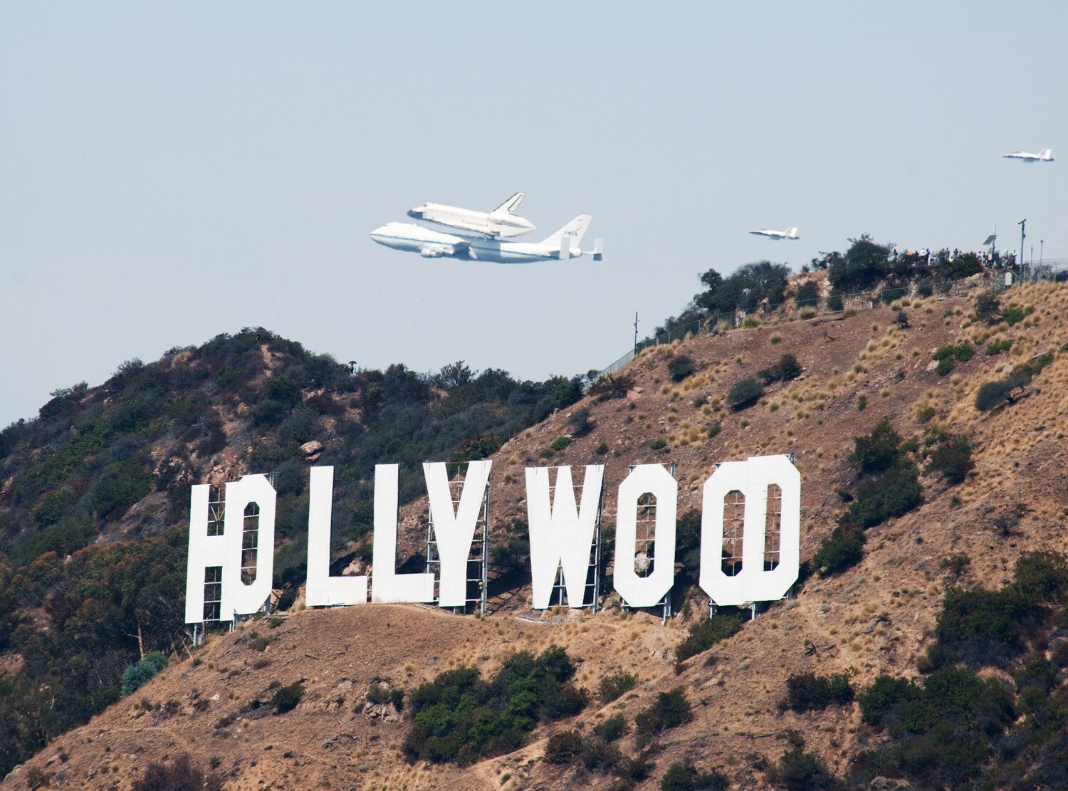 Eine Boing 747 fliegt mit dem Space Shuttle Endeavour auf dem Rücken über dem Hollywood-Schild