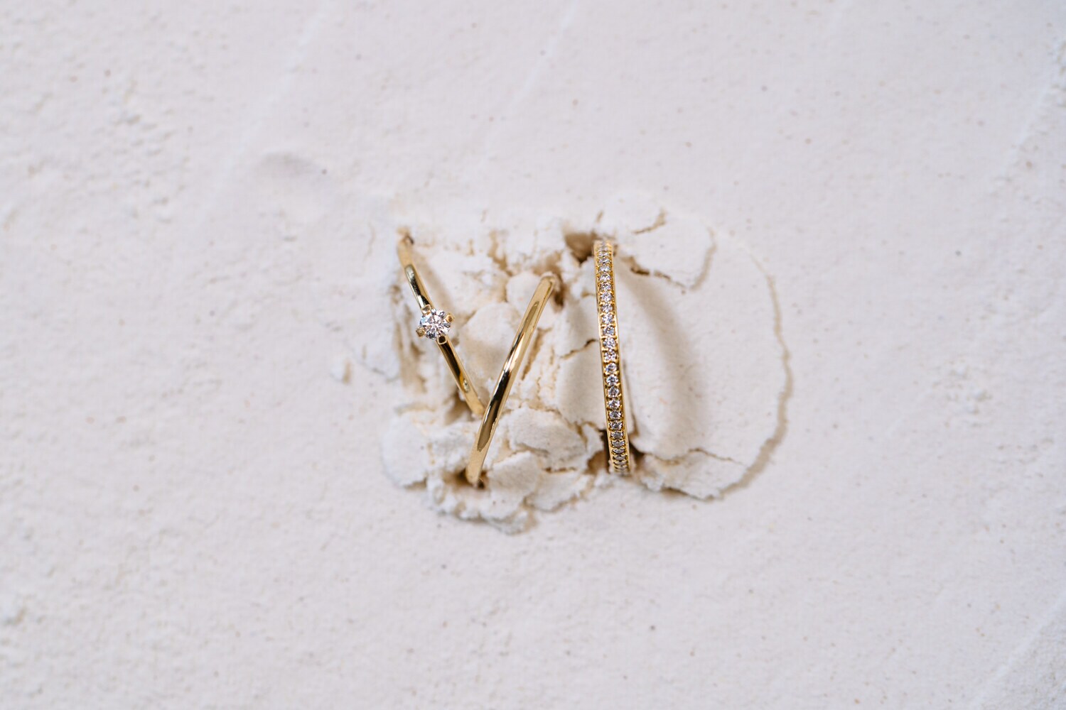 Drei goldene Ringe, die aus einer mehlartigen Oberfläche ragen