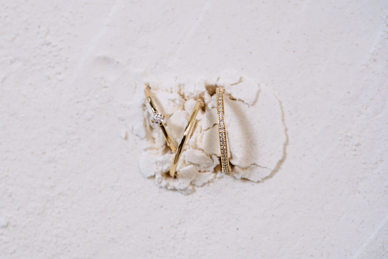 Drei goldene Ringe, die aus einer mehlartigen Oberfläche ragen Drei goldene Ringe, die aus einer mehlartigen Oberfläche ragen