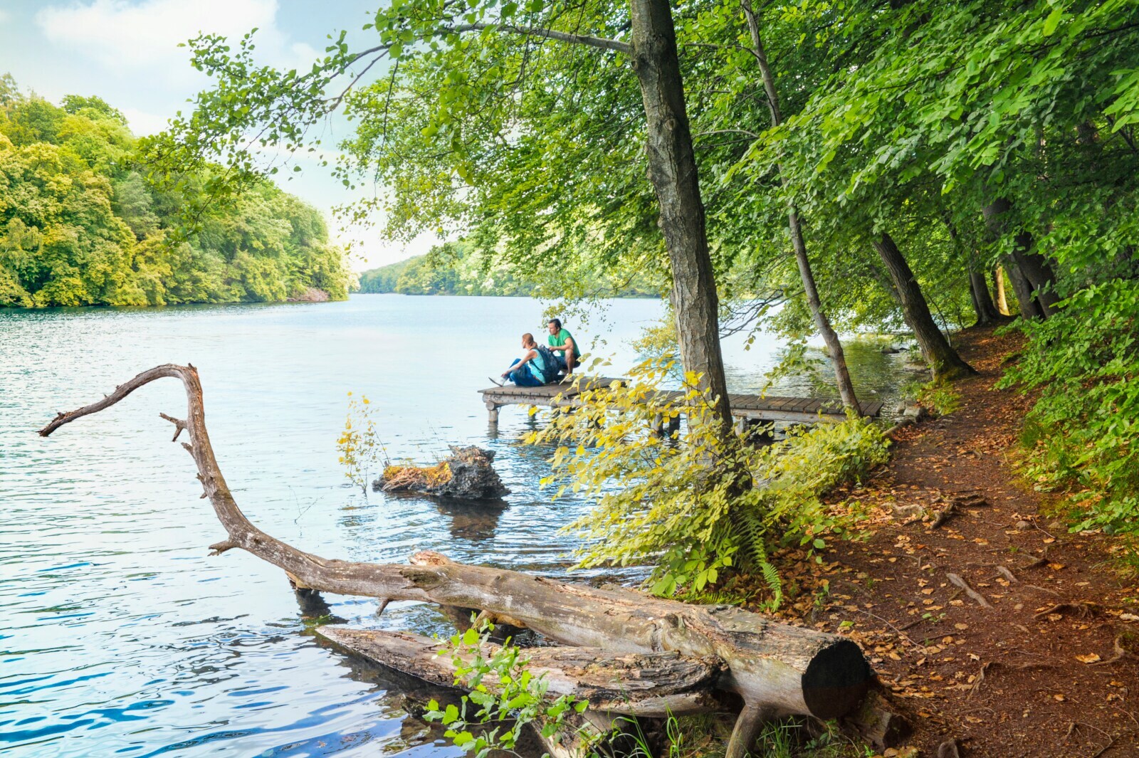 Wanderer pausieren auf einem Steg am Schmalen Luzin im Naturpark Feldberger Seenlandschaft