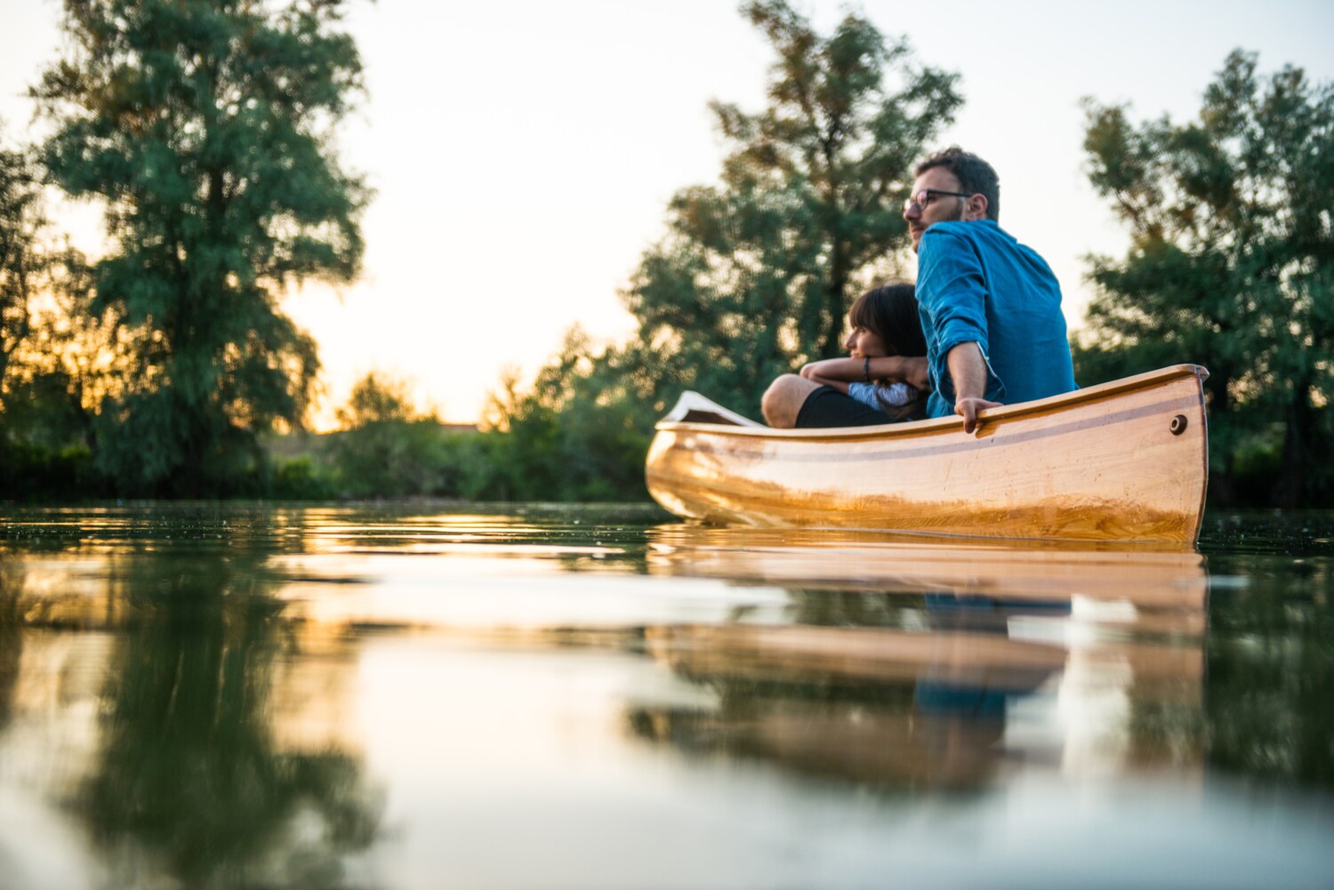 Ein Paar treibt in einem Kanu bei Sonnenuntergang auf einem See.