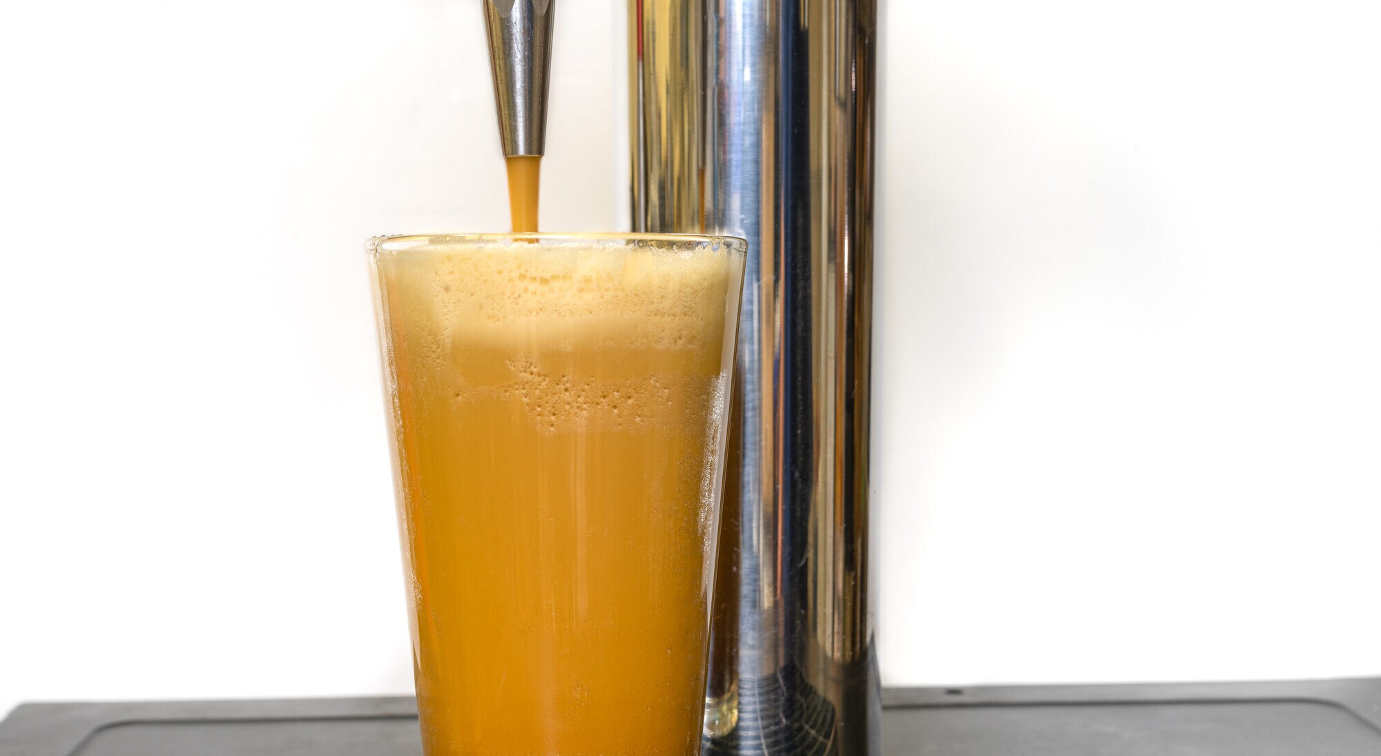 Nitro Cold Brew Kaffee, der in ein klares Glas mit feinen Stickstoffblasen und einer glatten Textur auf einem Fasskaffeespender gegossen wird