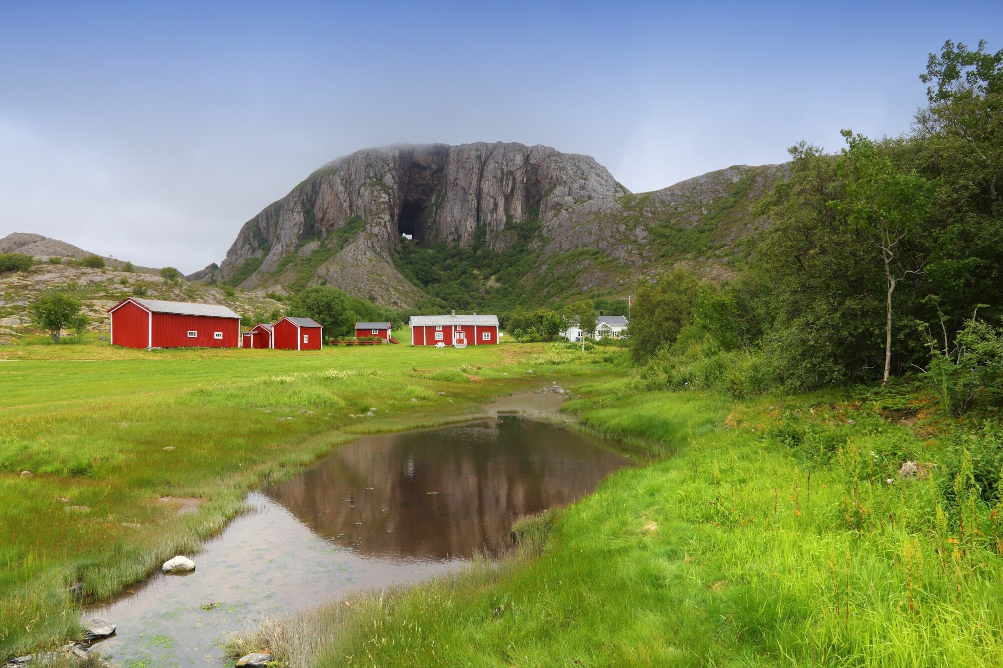 Häuser stehen auf einer Wiese vor dem Torghatten Häuser stehen auf einer Wiese vor dem Torghatten