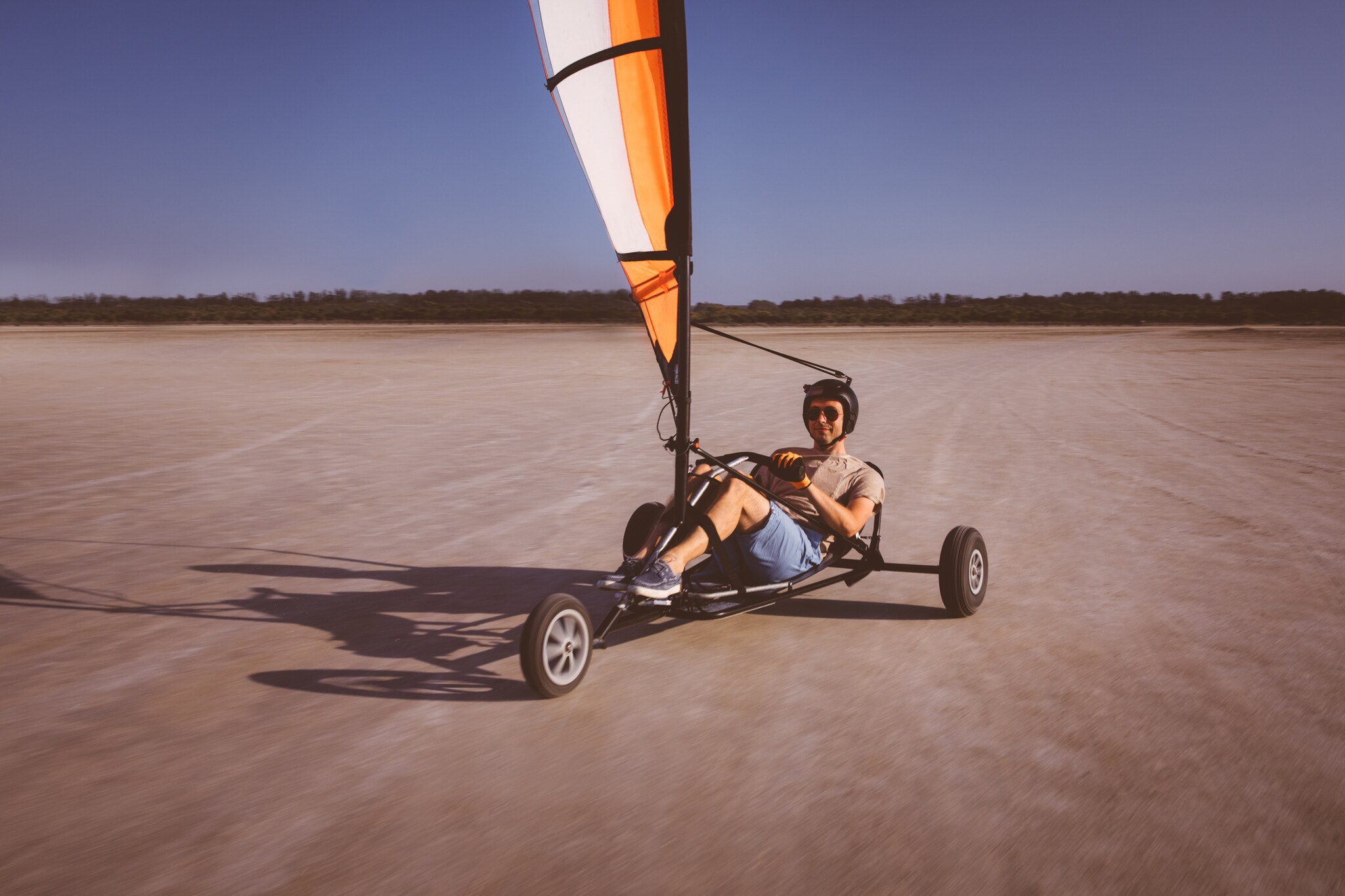 Ein Strandsegler an einem Strand bei blauem Himmel.