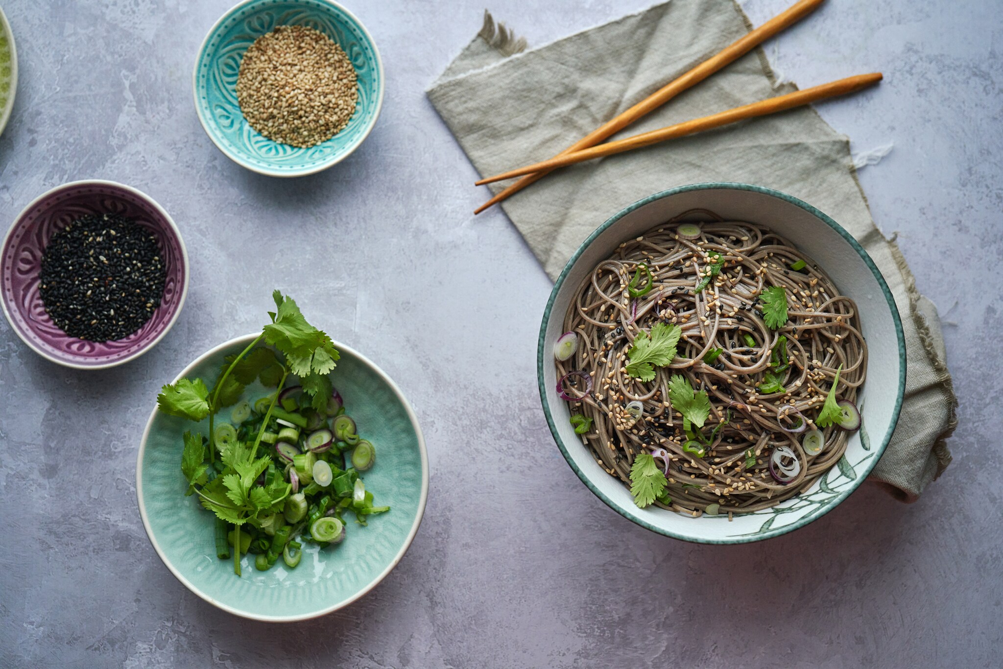 Ein Nudelgericht, frische Kräuter und eine Schale mit Soße.