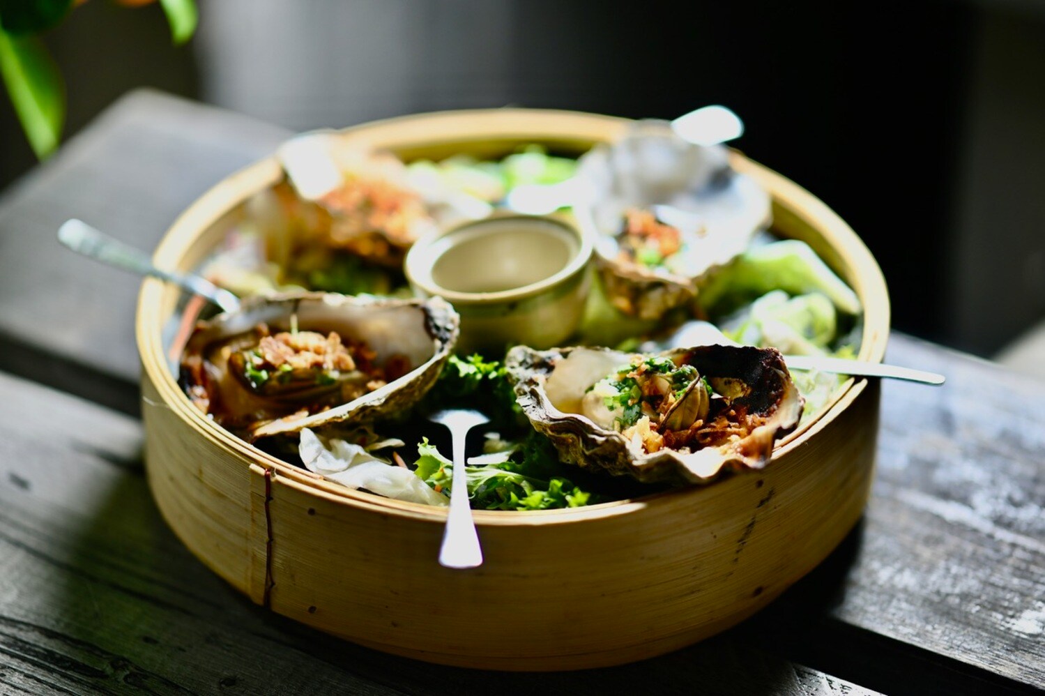 Eine Bambusschale mit gefüllten Austernschalen.