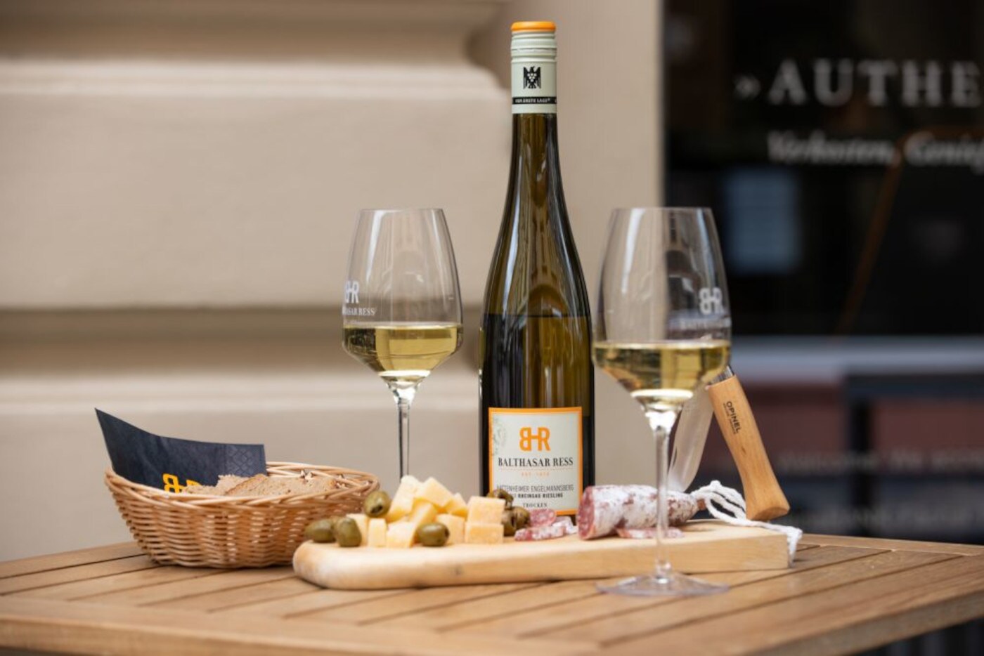 Eine Weinflasche, zwei gefüllte Gläser und Snacks auf einem Holztisch