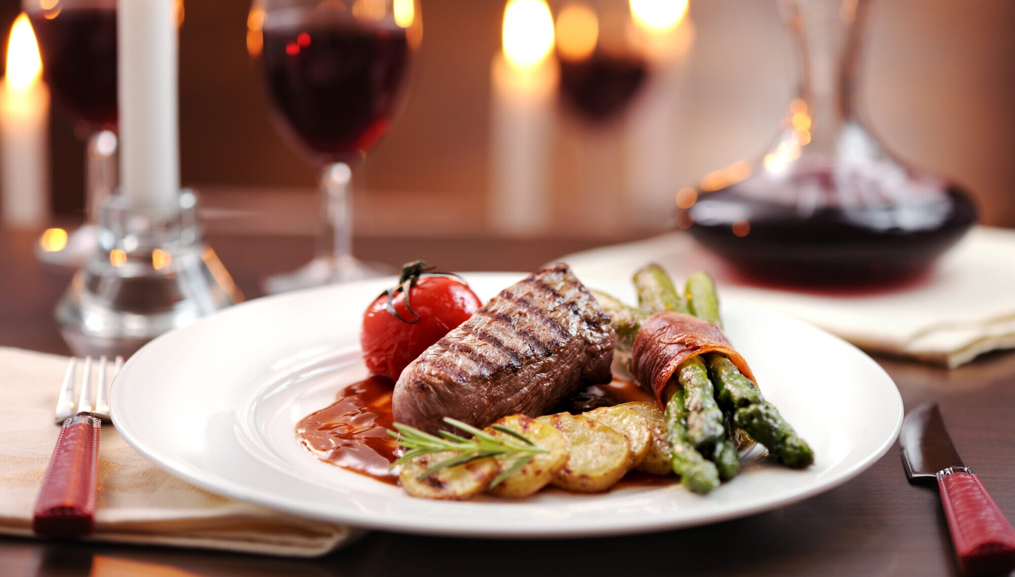 Ein Teller mit Steak, grünem Spargel und Rotwein