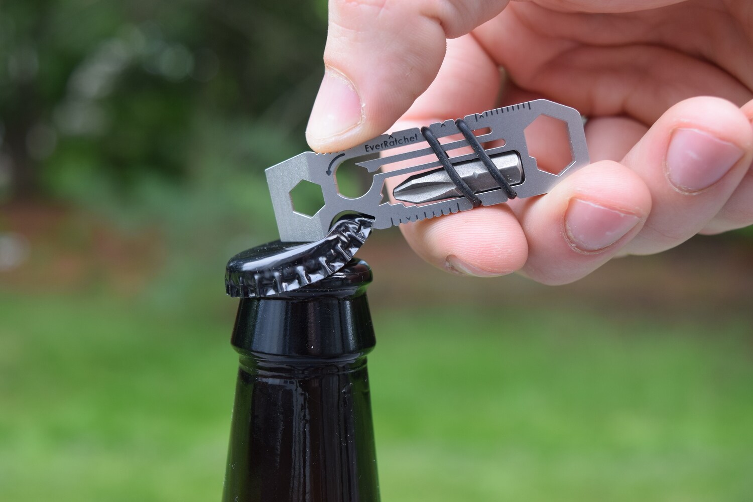 Mit einem Multitool wird eine Flasche mit Kronkorken geöffnet.