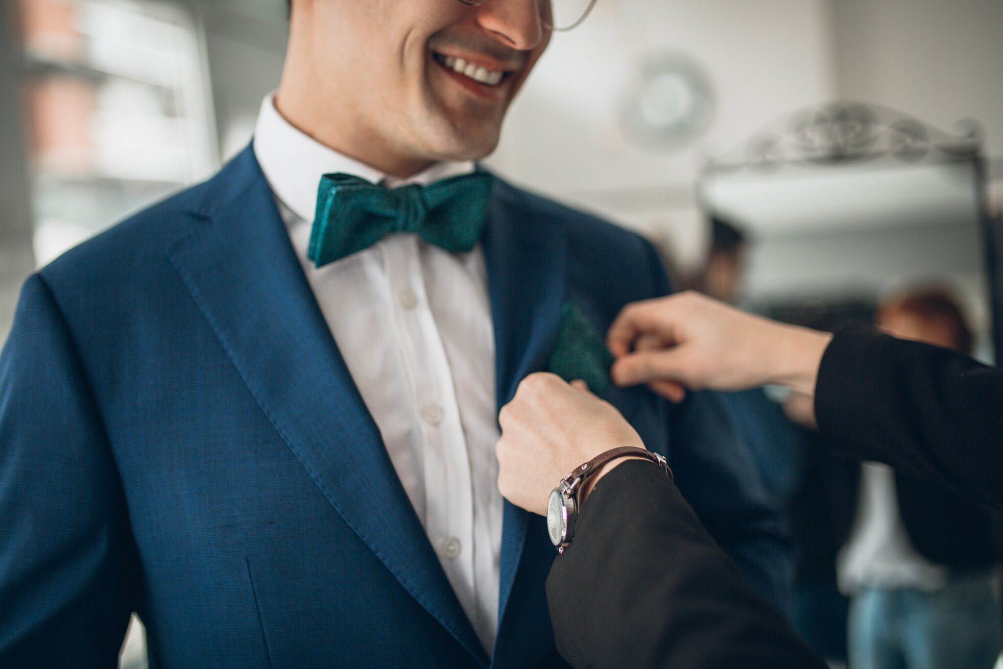 Einem Mann im Anzug wird das Einstecktuch in den Anzug gesteckt