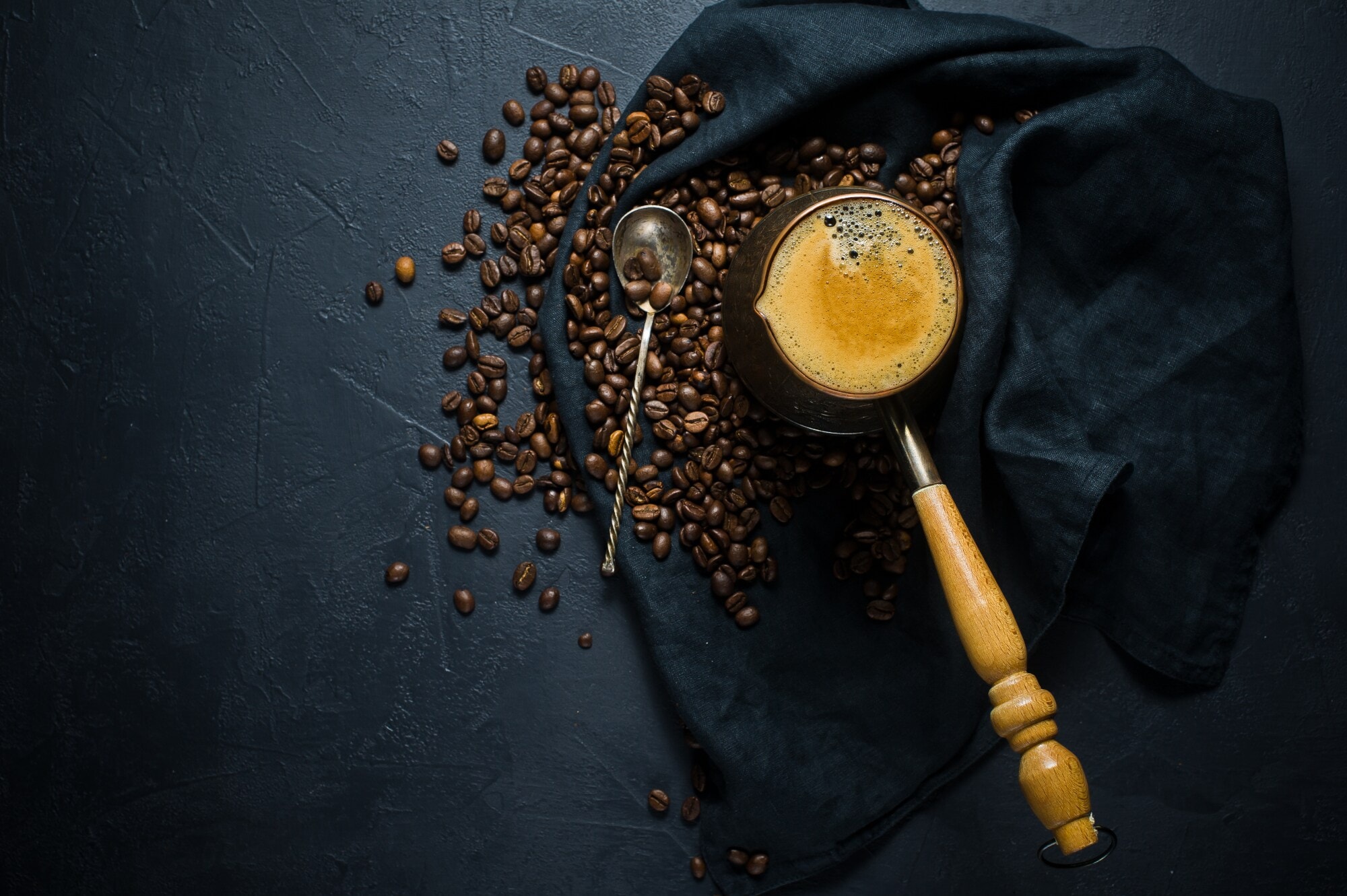 Geröstete Bohnen und frisch gebrühter Kaffee auf einem dunklen Tuch angerichtet Geröstete Bohnen und frisch gebrühter Kaffee auf einem dunklen Tuch angerichtet