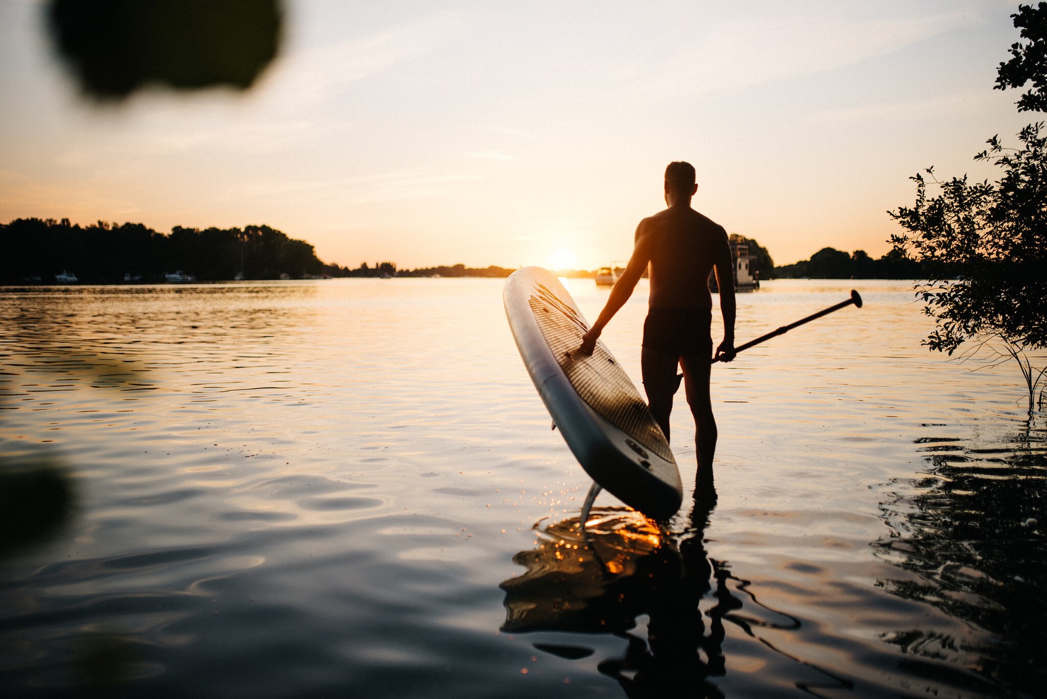 Mann trägt ein SUP Board ins Wasser